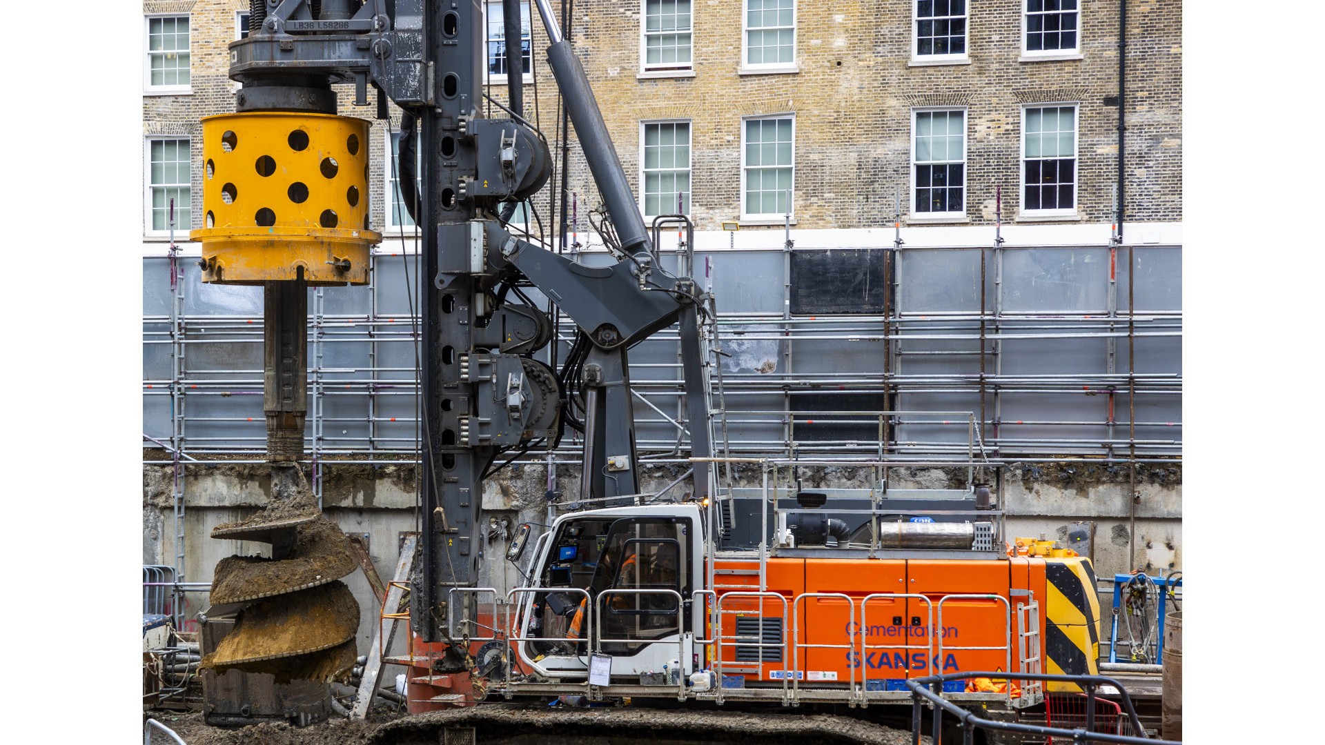 Cementation Skanska piling in central London Large construction drill rig with orange Skanska equipment in urban building site.
