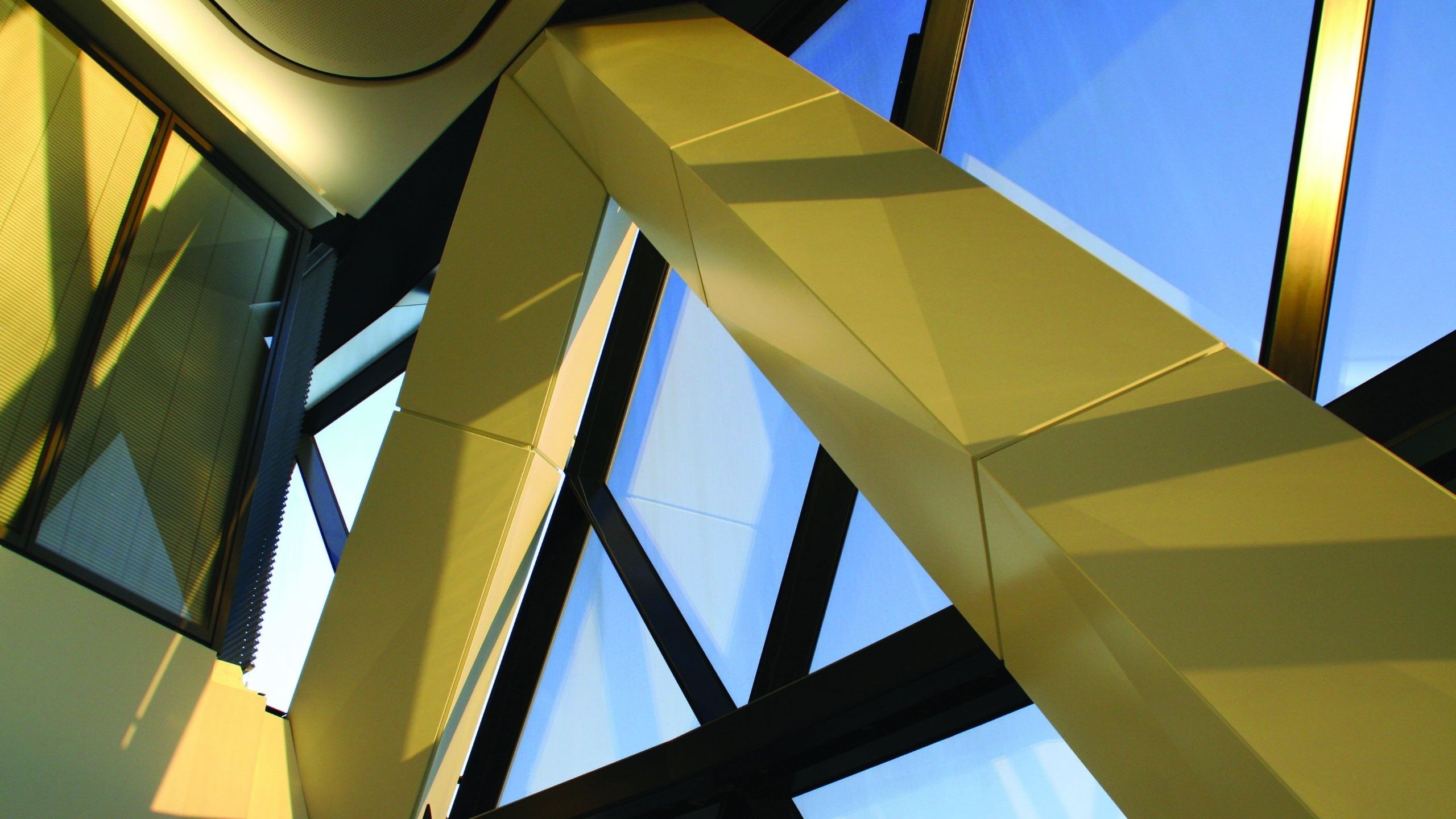 Interior shot taken within The Gherkin Modern building interior with large yellow structural beams and glass windows.