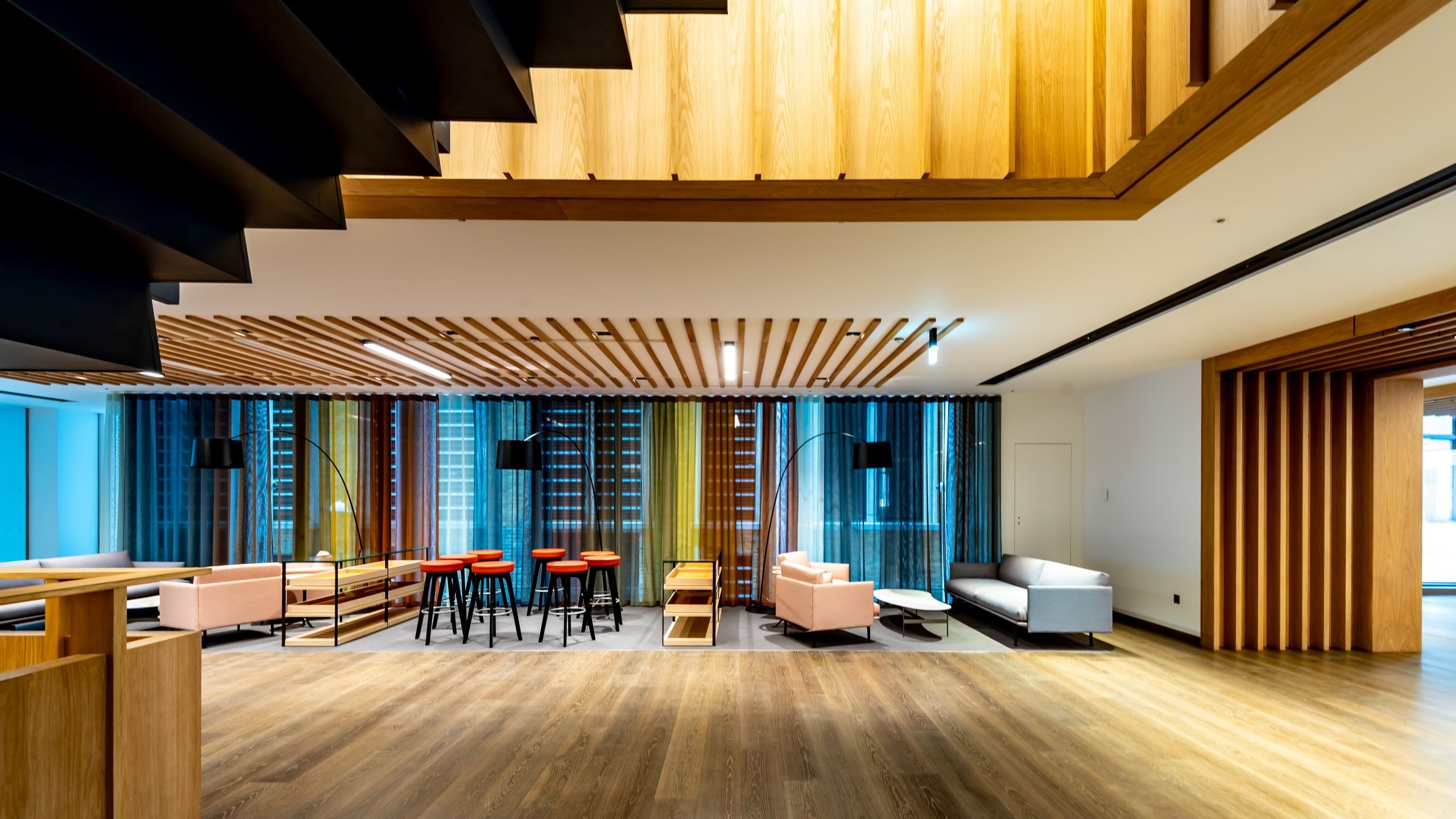 Modern office lounge with wood accents Modern office lounge with wooden accents, colorful seating, and large windows.