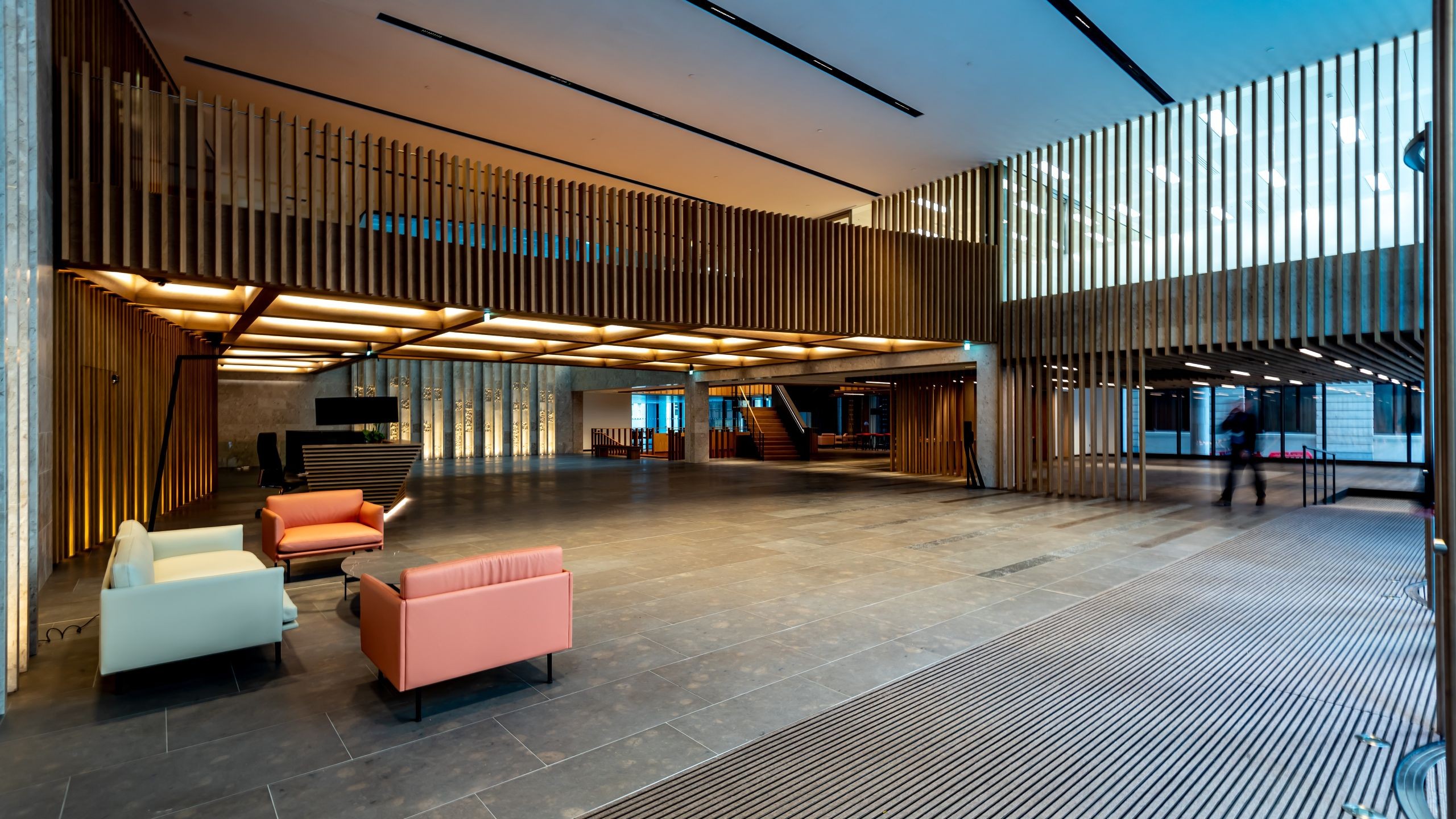Modern spacious office lobby with minimalist furniture and vertical wood panel accents.