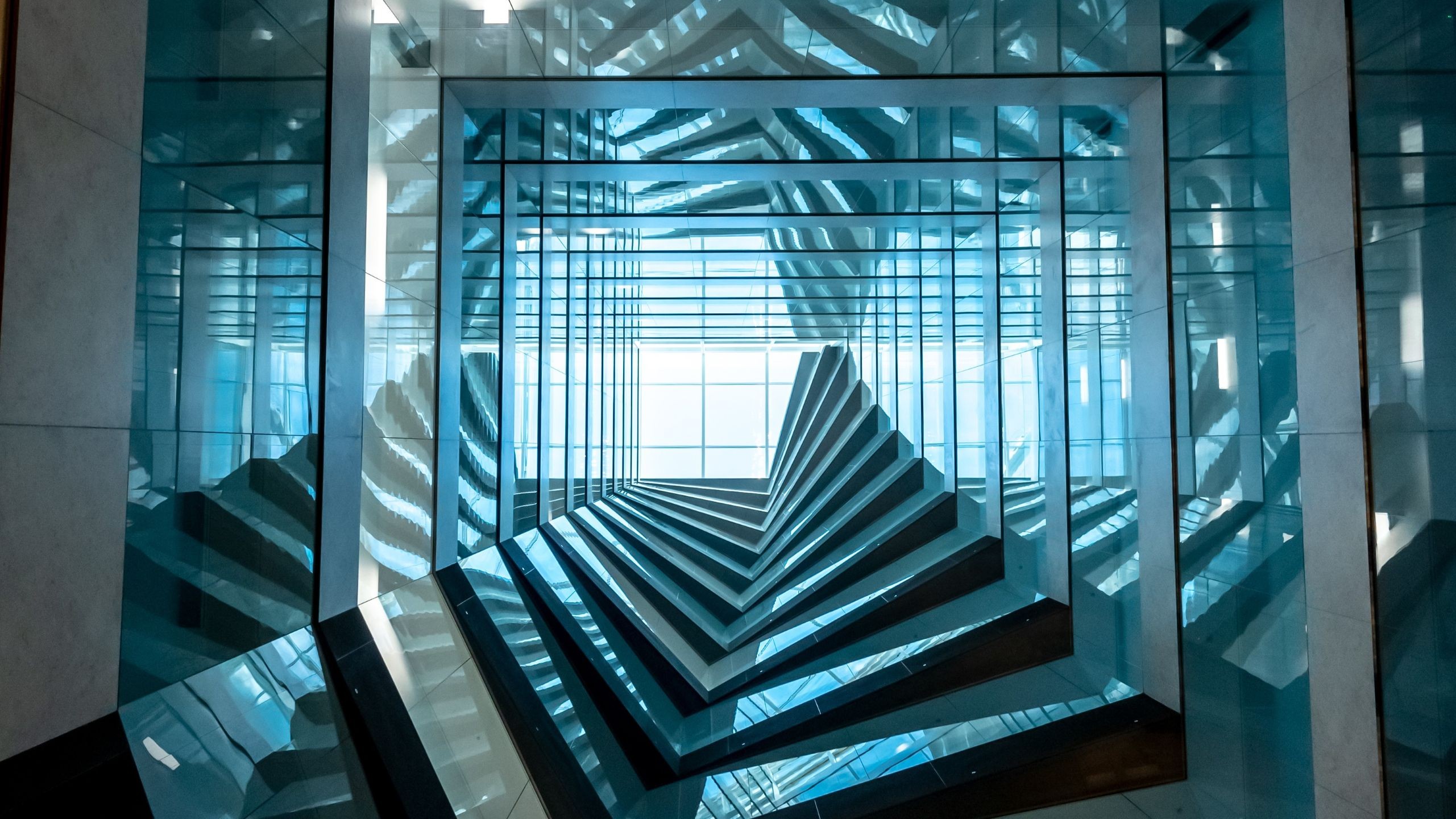 Abstract geometric pattern of reflective glass panels forming a tunnel-like structure.