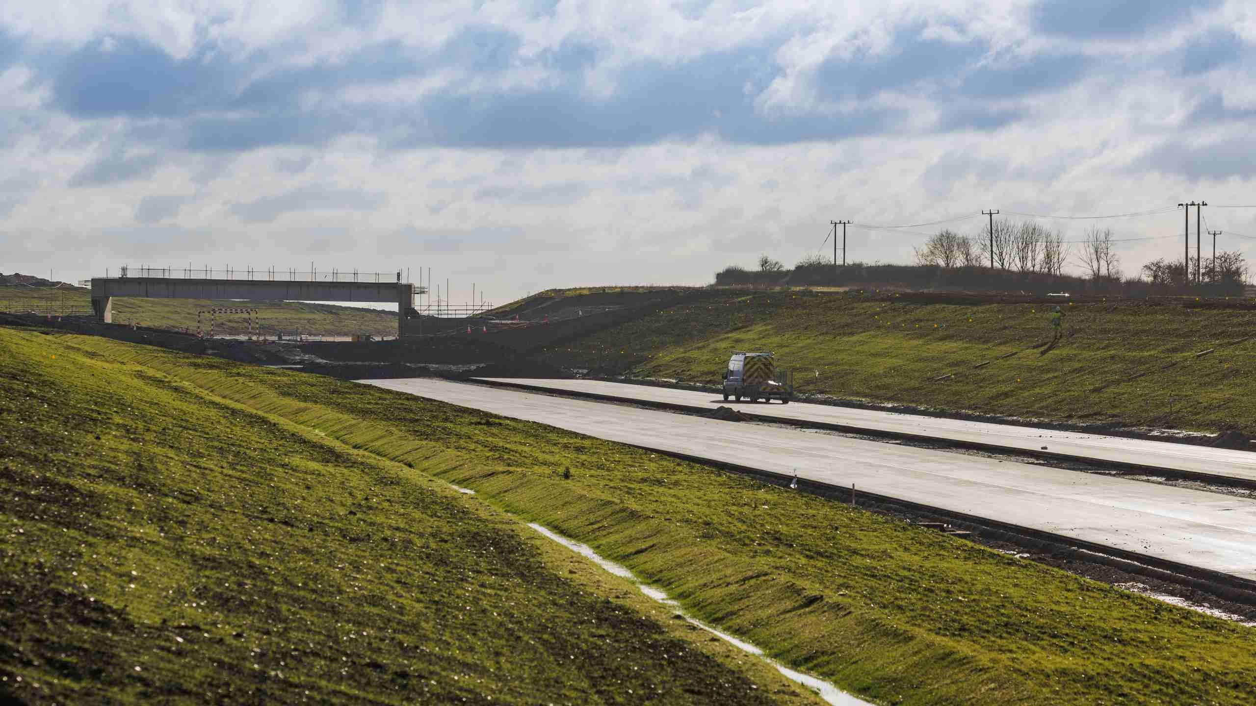 A well-lit underground railway tunnel under construction with visible tracks and concrete walls.