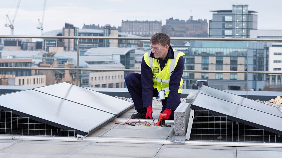 Technician Installing Solar Panels on Urban Rooftop A technician in safety gear inspects rooftop solar panels against an urban cityscape backdrop.