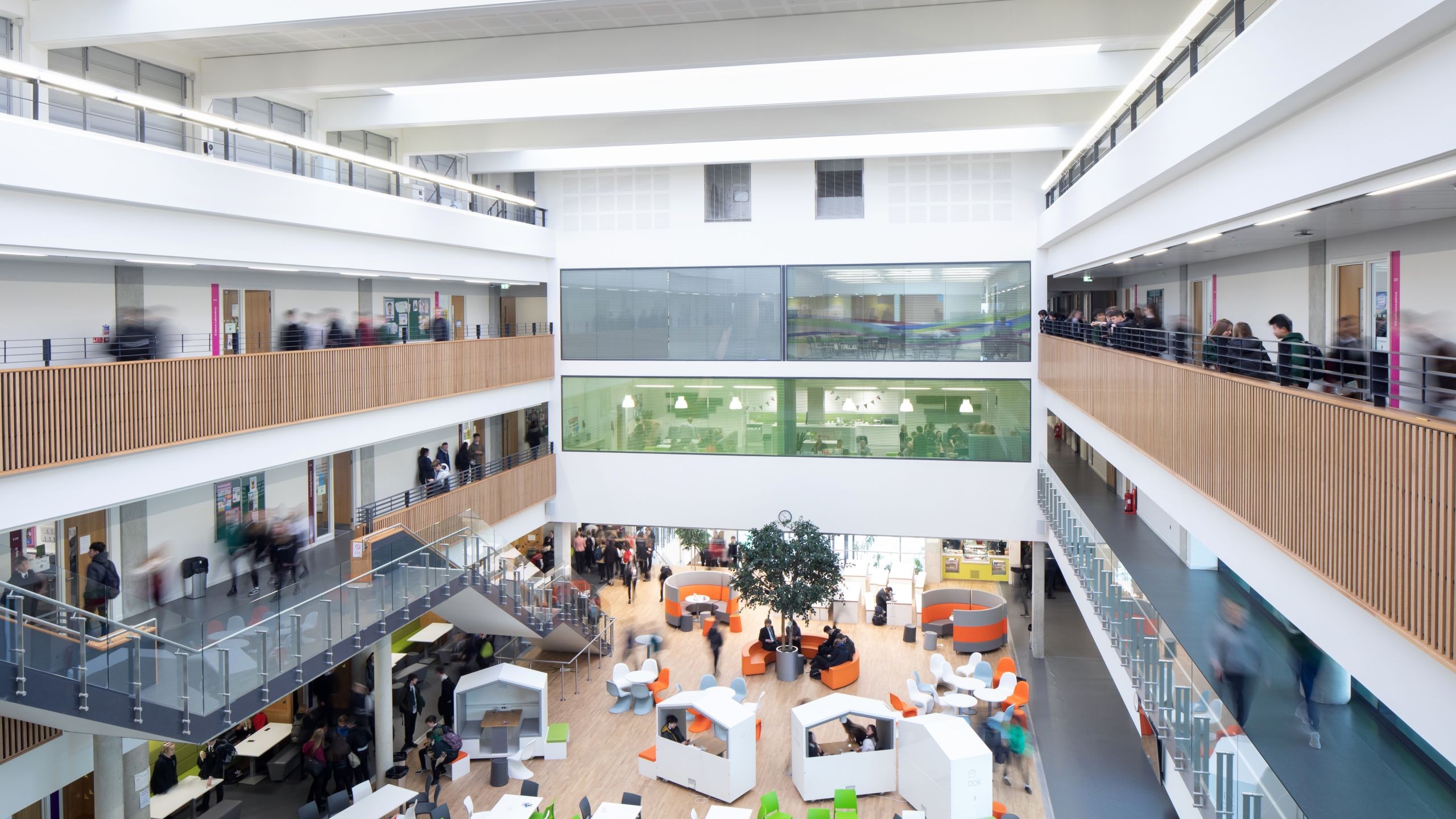 Edinburgh high school we maintain Modern open office atrium with multiple floors, glass walls, and people working.