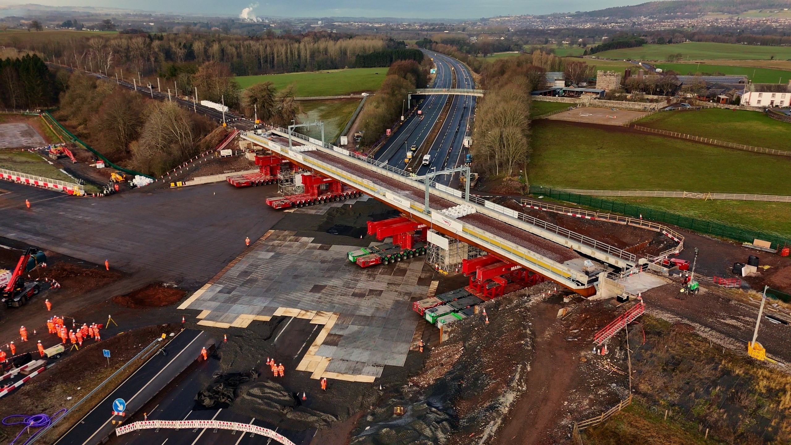 Aerial view of a highway bridge under construction with workers and machinery.