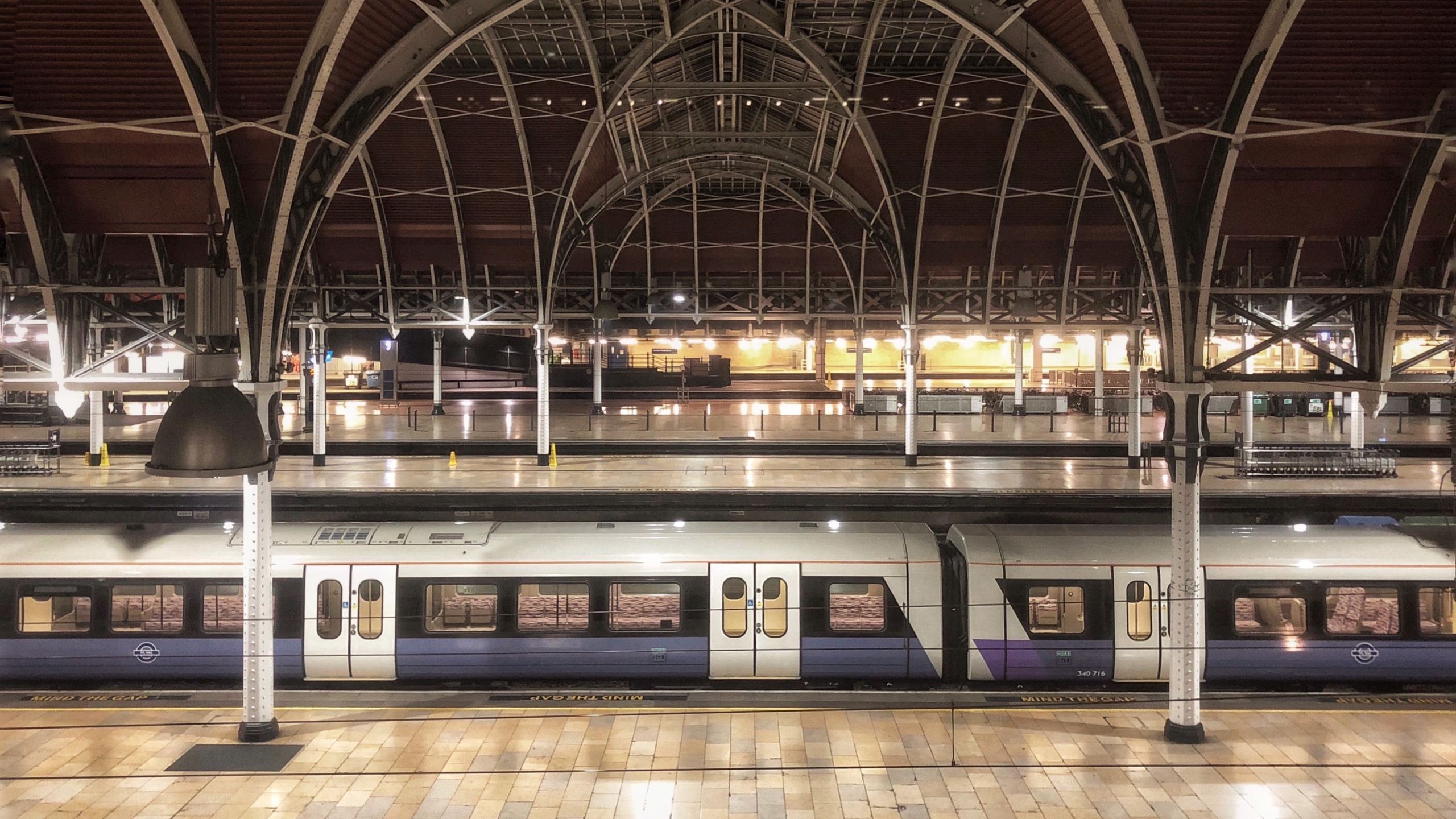 Modern Train Station Platform with Arched Roof Structure at Night Modern train parked at a spacious, well-lit train station with arched roof structure.