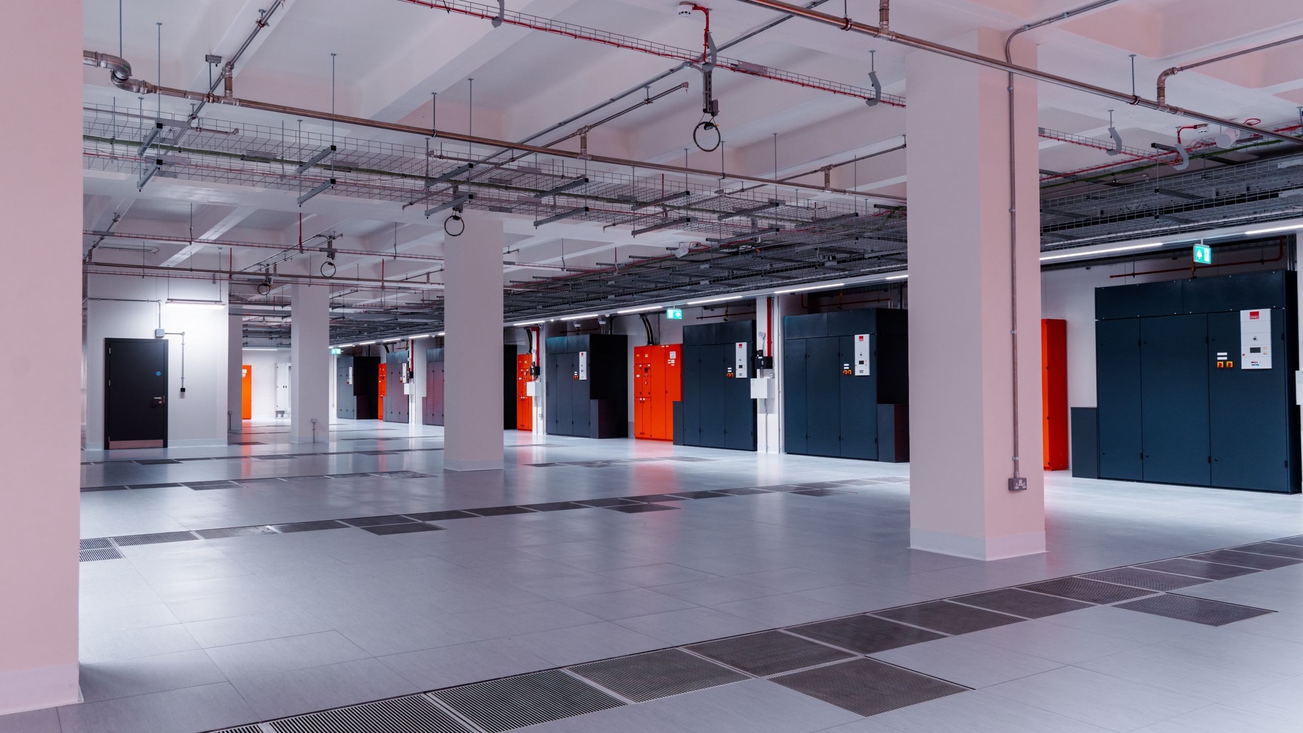 Telehouse South Spacious modern industrial basement with white pillars, tiled floor, and utility doors.