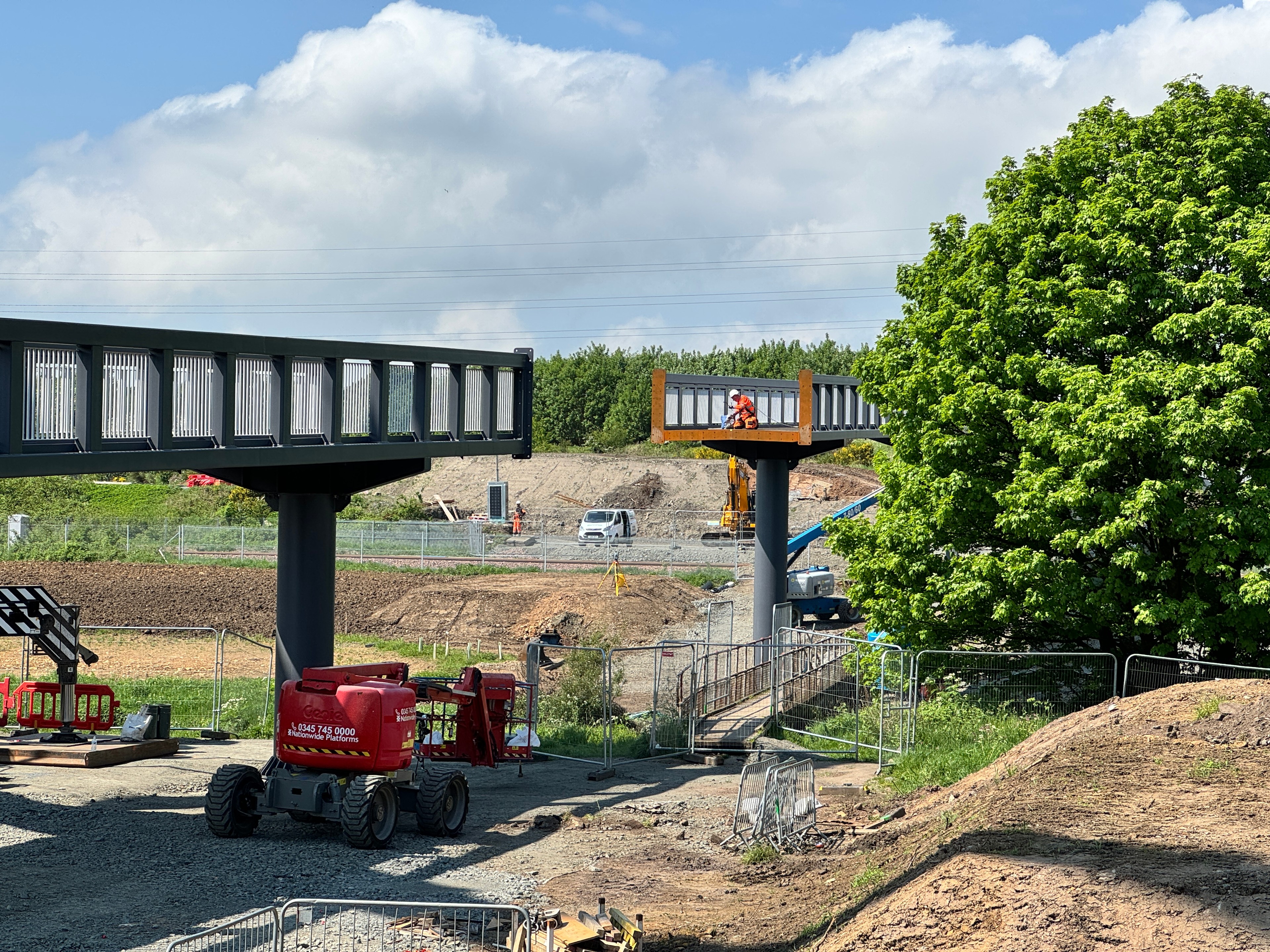 Construction site with elevated steel bridge sections and heavy machinery under clear sky.