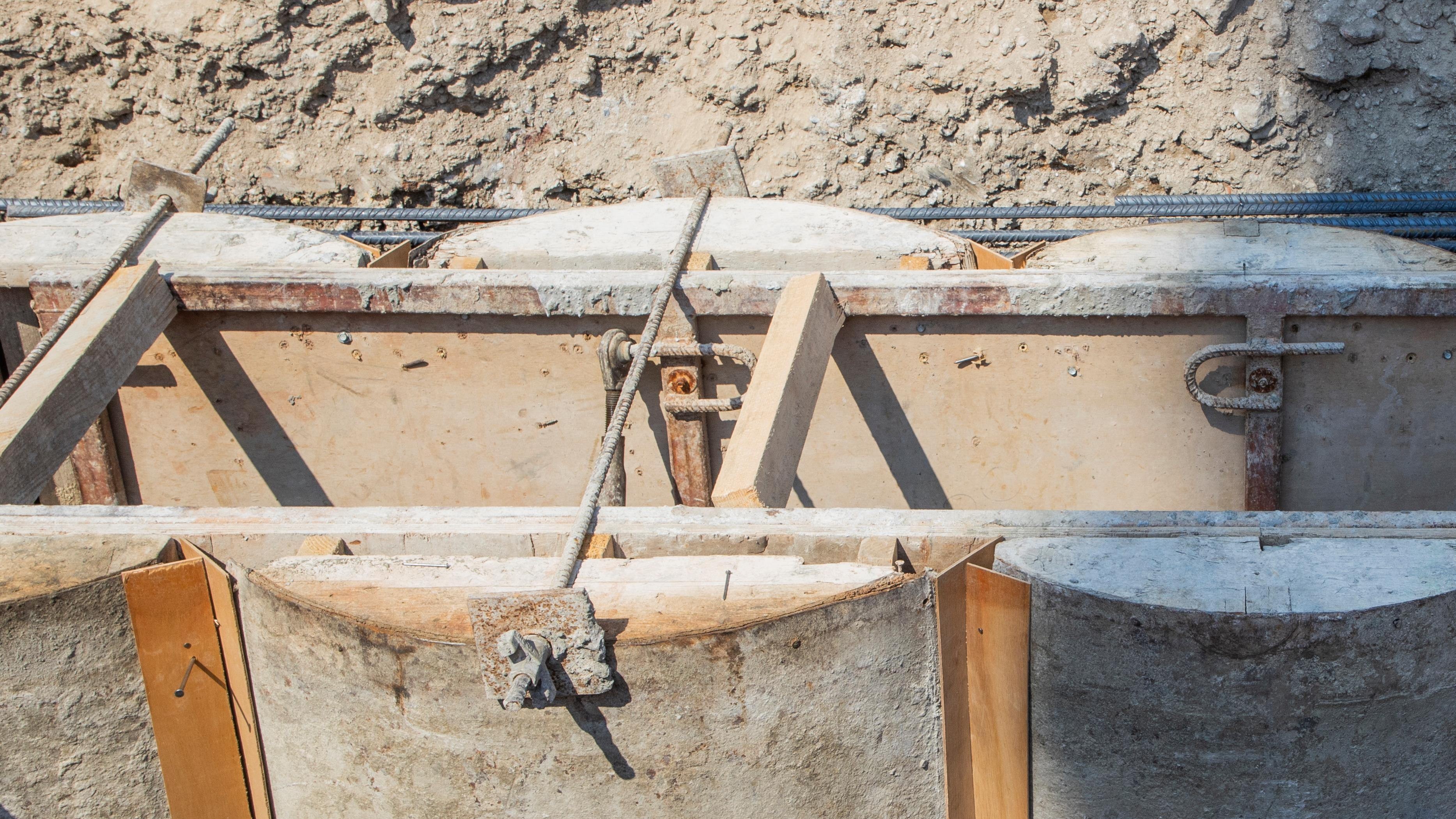 Concrete formwork with metal rods and wooden panels at a construction site.