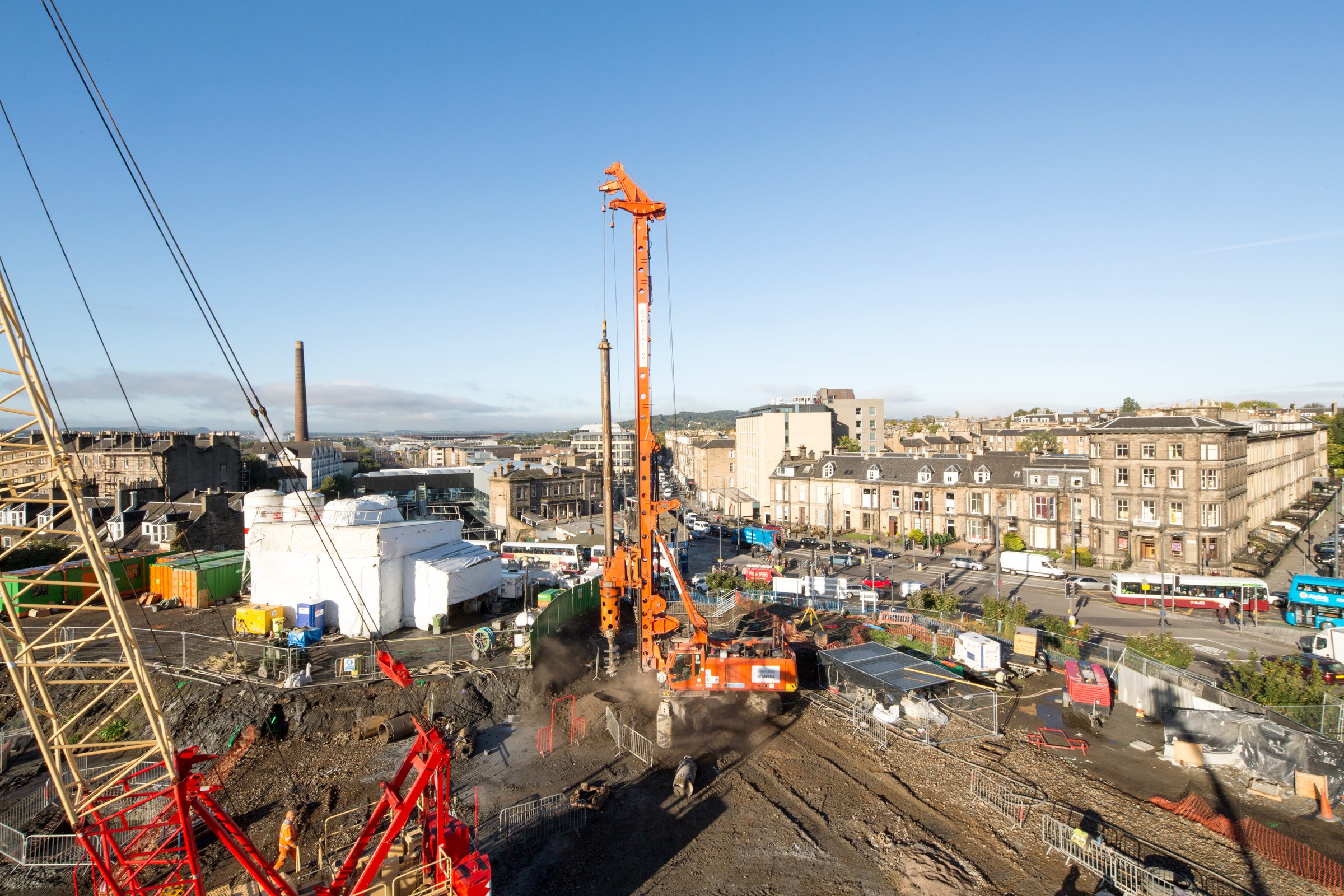 Haymarket Edinburgh Urban construction site with large orange drilling rig amidst buildings and clear blue sky.