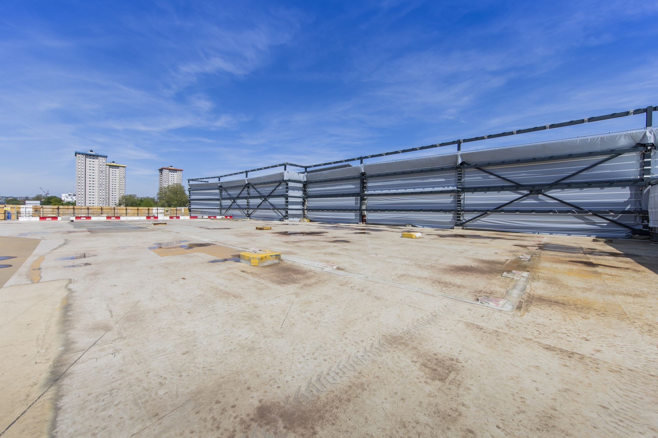 Construction site with concrete floor and blue sky background Empty rooftop with industrial ventilation units under a clear blue sky in an urban area.