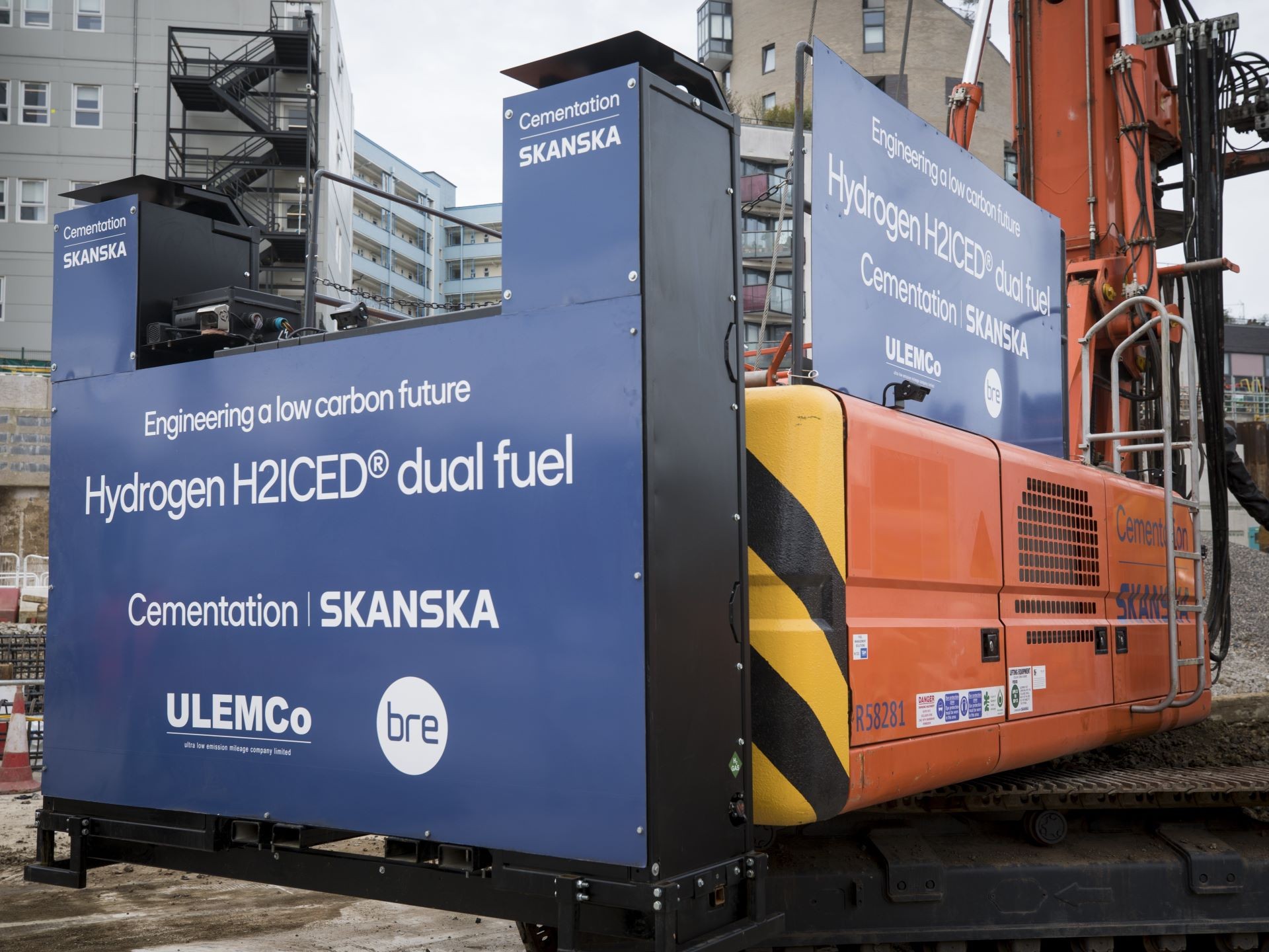 Hydrogen Dual Fuel Excavator by Skanska for Low Carbon Future Construction vehicle with blue panels promoting Hydrogen H2ICED dual fuel by Skanska.