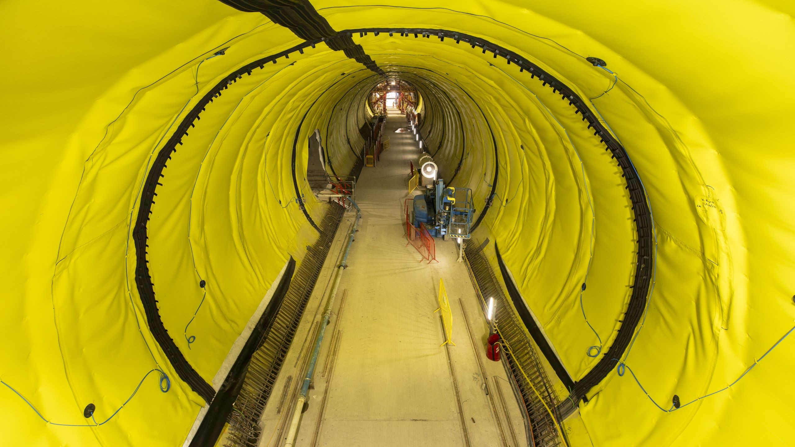 Tunnel Construction Site with Bright Yellow Protective Lining Construction tunnel lined with yellow waterproof membrane and equipment inside.