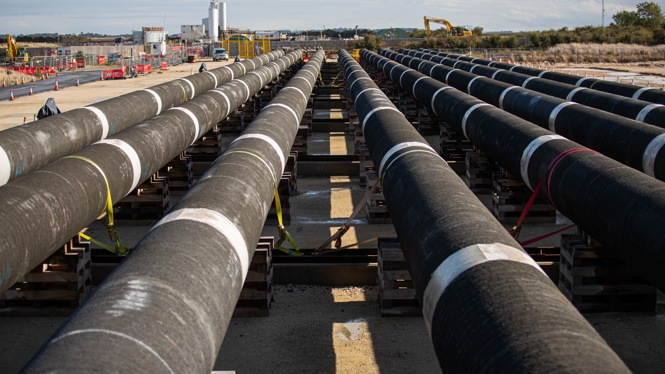 This will be the longest gas pipeline in a tunnel, inserted in a single string, in the world. Large black industrial pipes with yellow ends laid out on pallets at a construction site.
