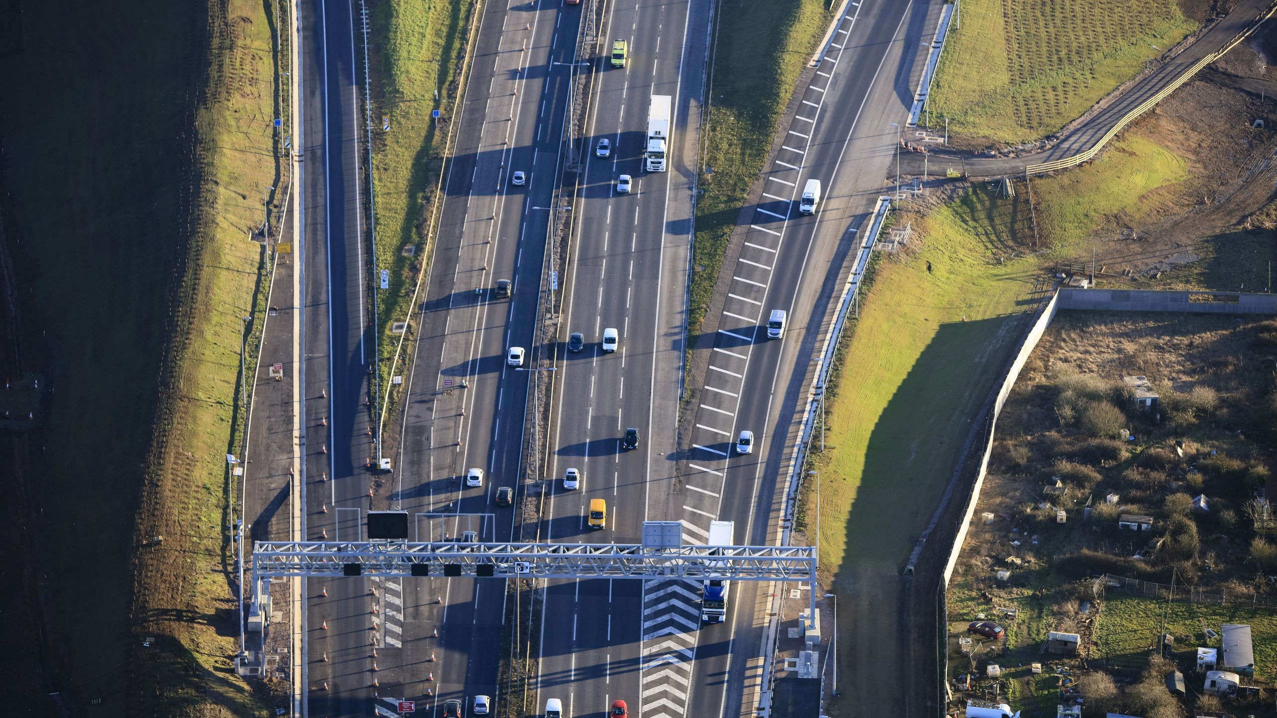 Aerial view of a busy multi-lane highway with cars and green roadside areas.