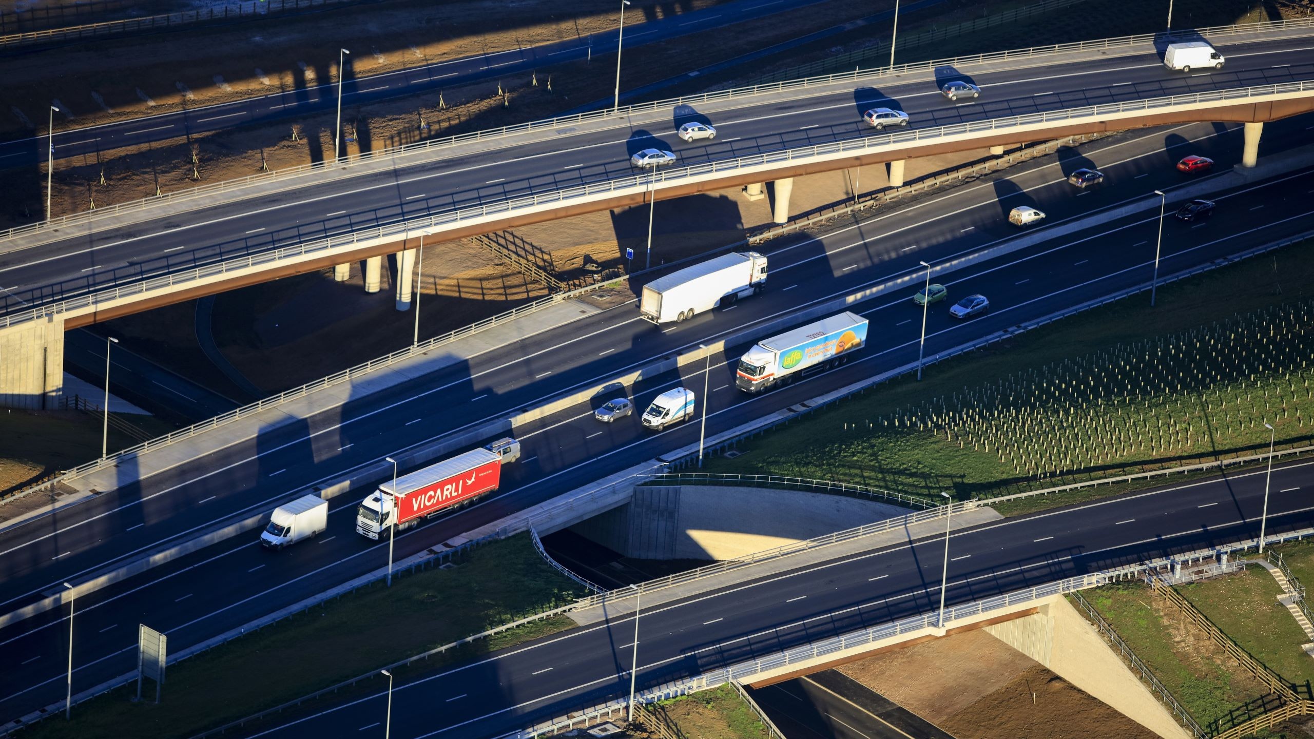 Aerial view of busy highway overpasses with trucks and cars in daylight traffic.