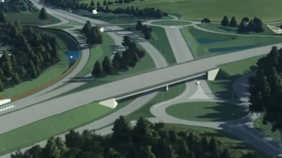 Aerial view of a highway overpass surrounded by greenery and trees in a rural area.