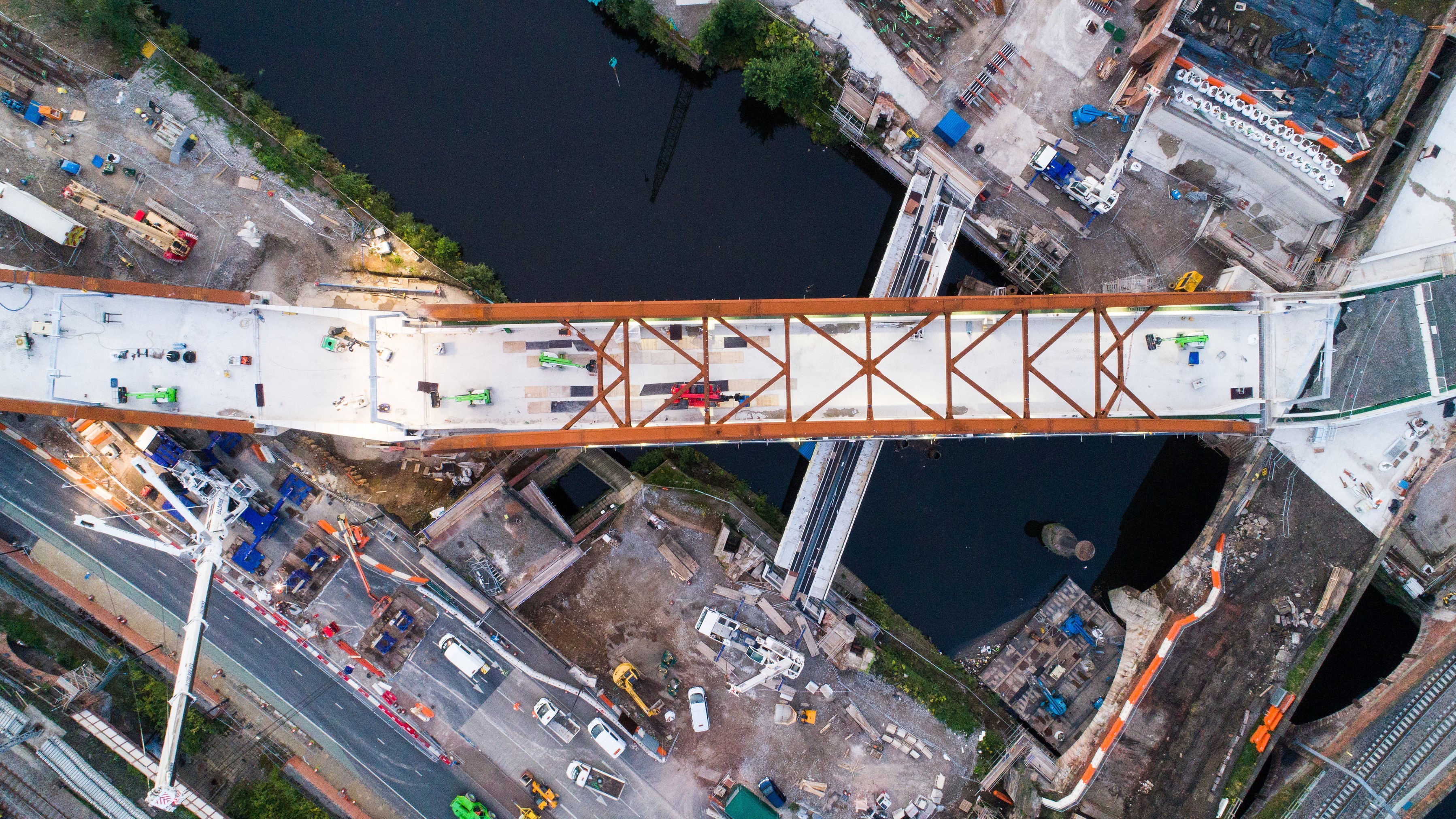 Aerial view of a bridge under construction over a river with construction vehicles.