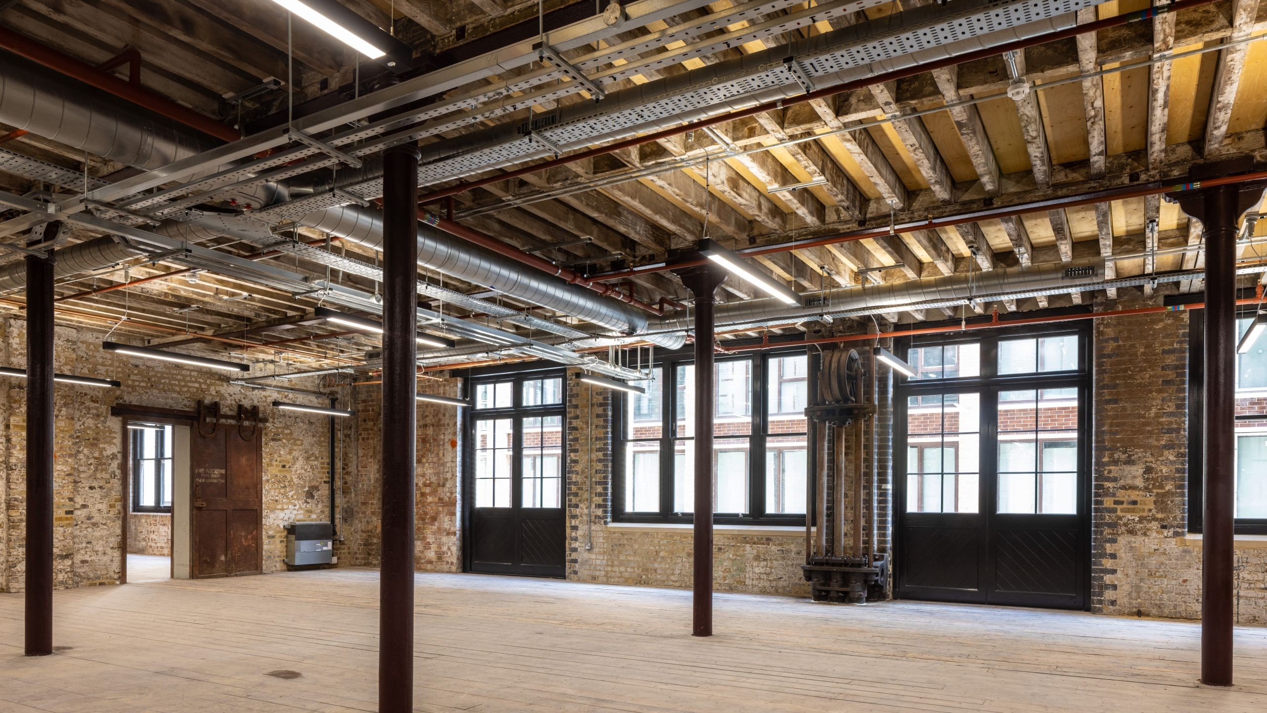 Spacious Industrial Loft with Exposed Beams and Large Windows Spacious industrial loft with exposed brick walls, wooden beams, and large windows.