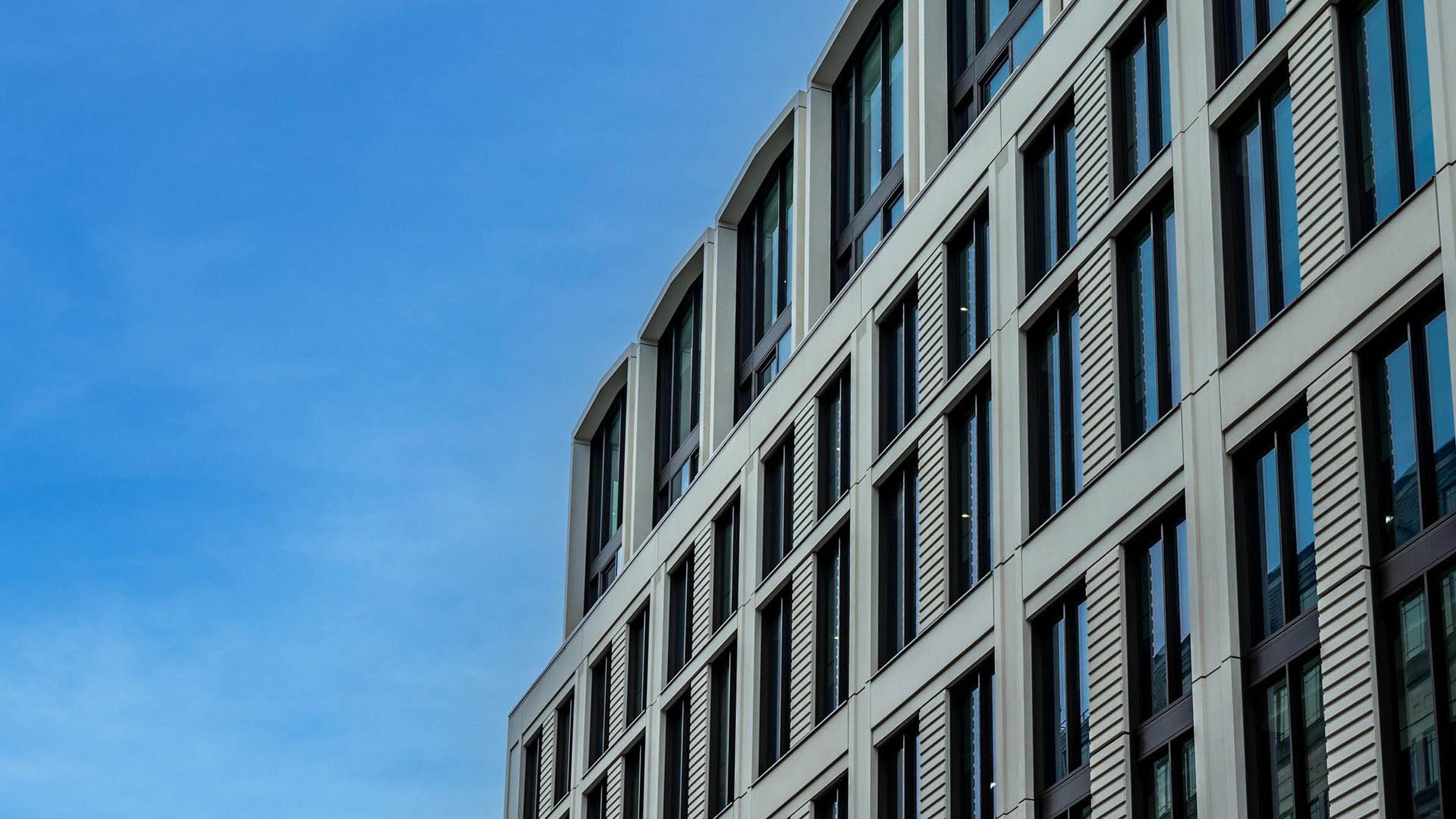 The Earnshaw Building Modern curved building with glass windows against a clear blue sky.