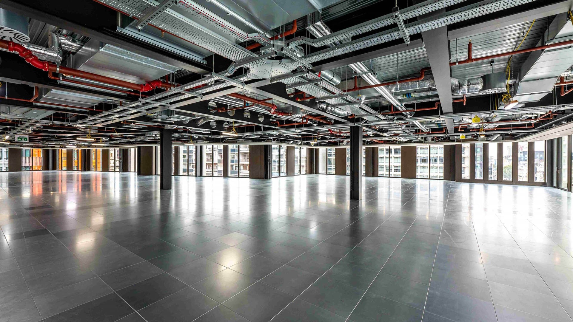 Modern open-plan office space with exposed ceilings and large windows for natural light.