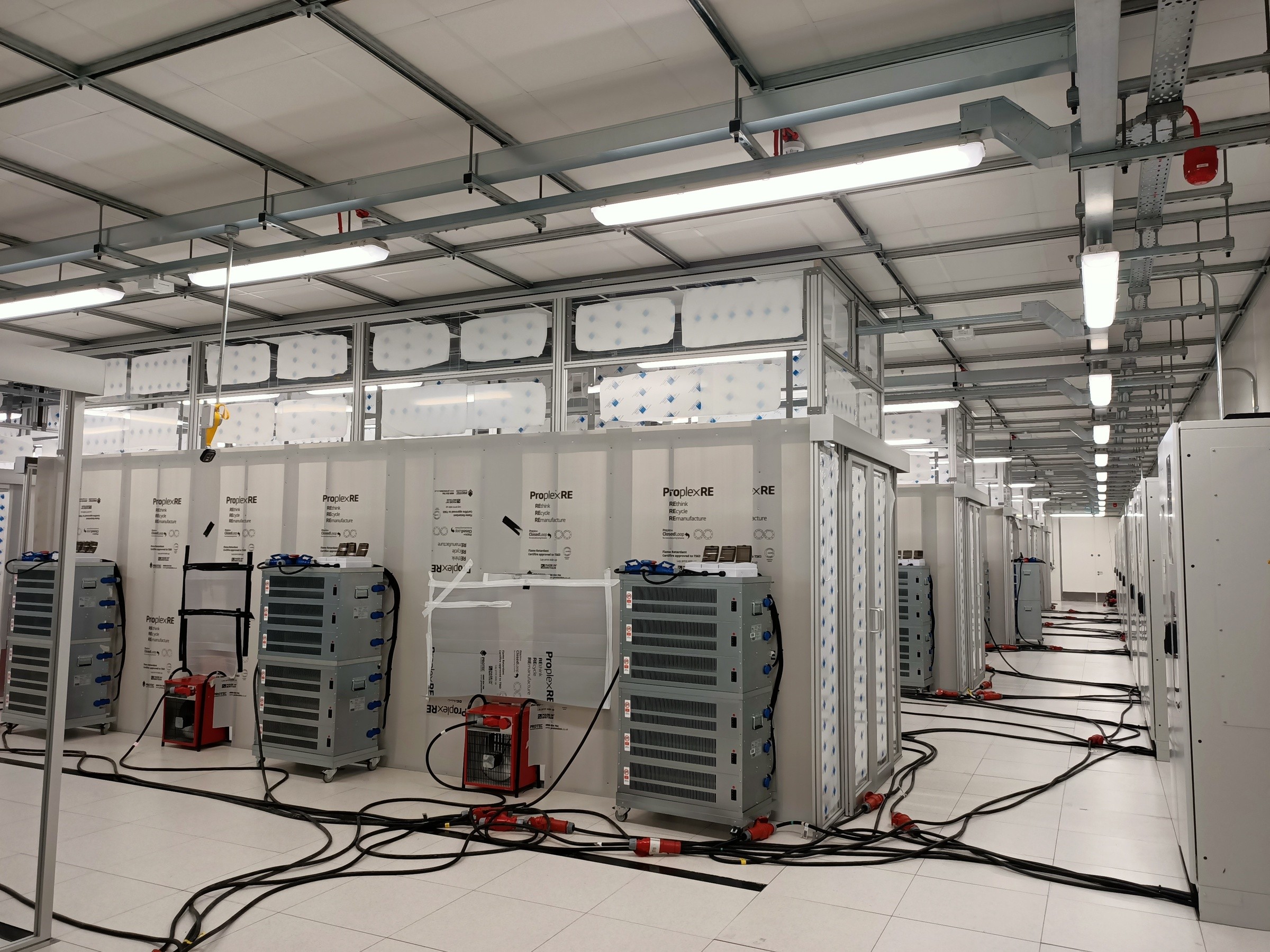 Virtus 11 Data center room with server racks, cables, and cooling equipment under bright lights.