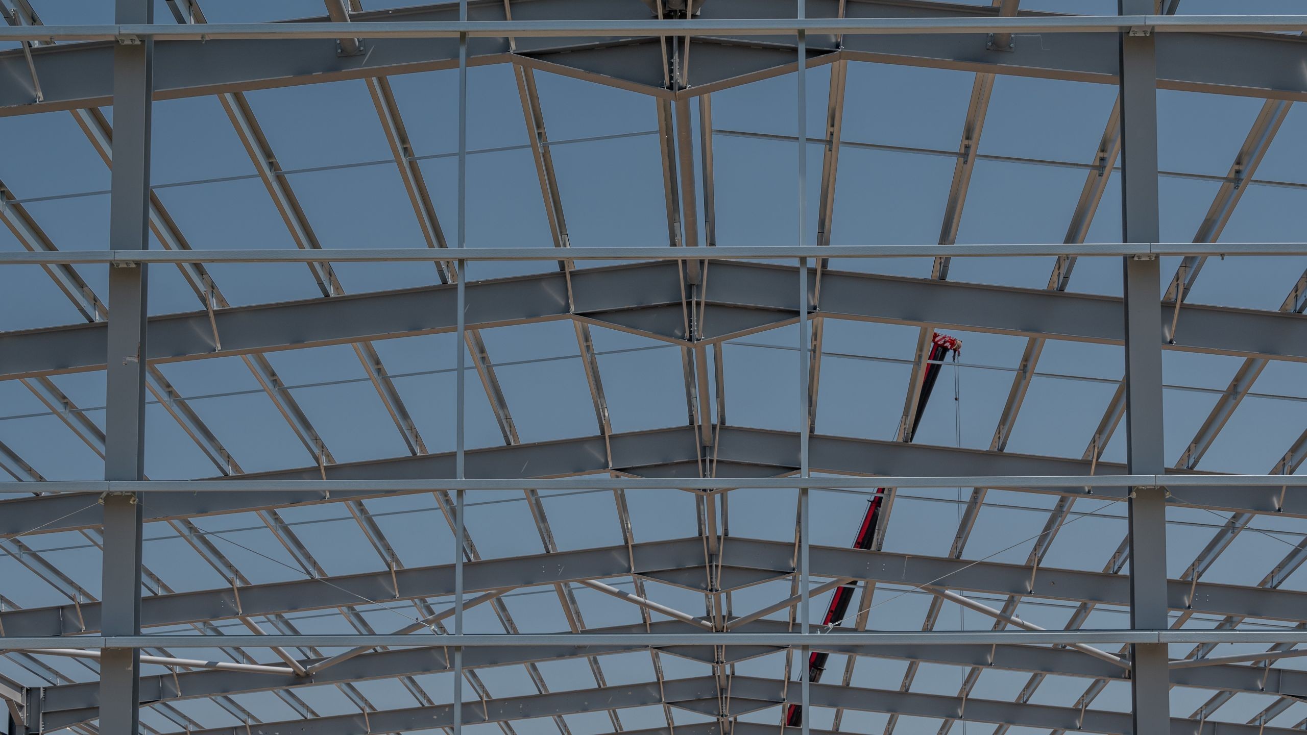 Steel framework of a large industrial building under construction against a clear sky.