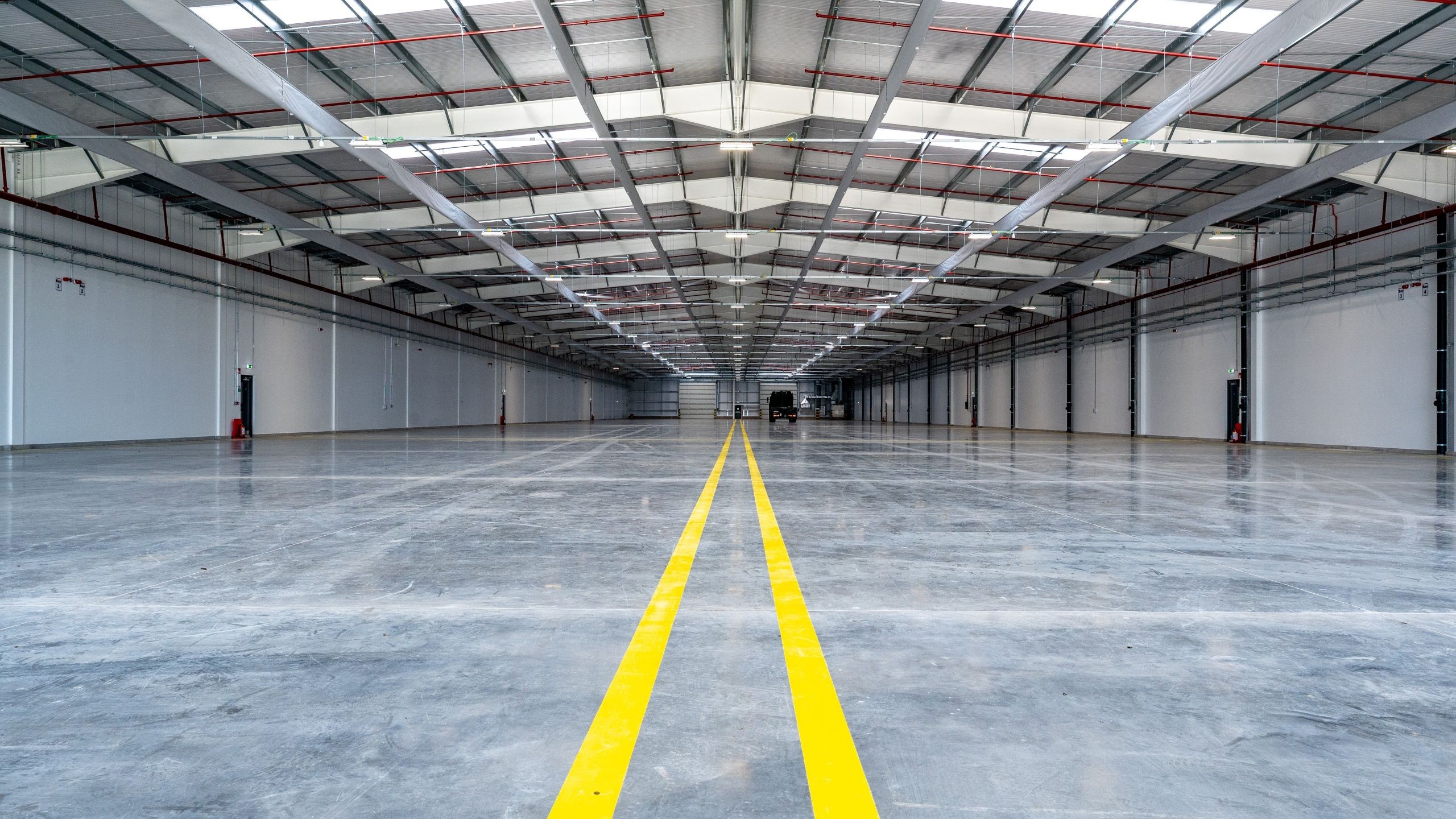 Spacious empty warehouse interior with polished concrete floor and yellow lines.
