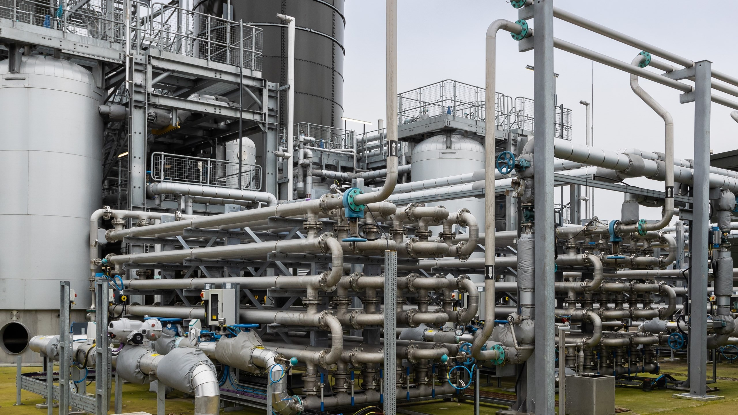 Industrial facility with complex metal pipes and tanks for chemical processing.