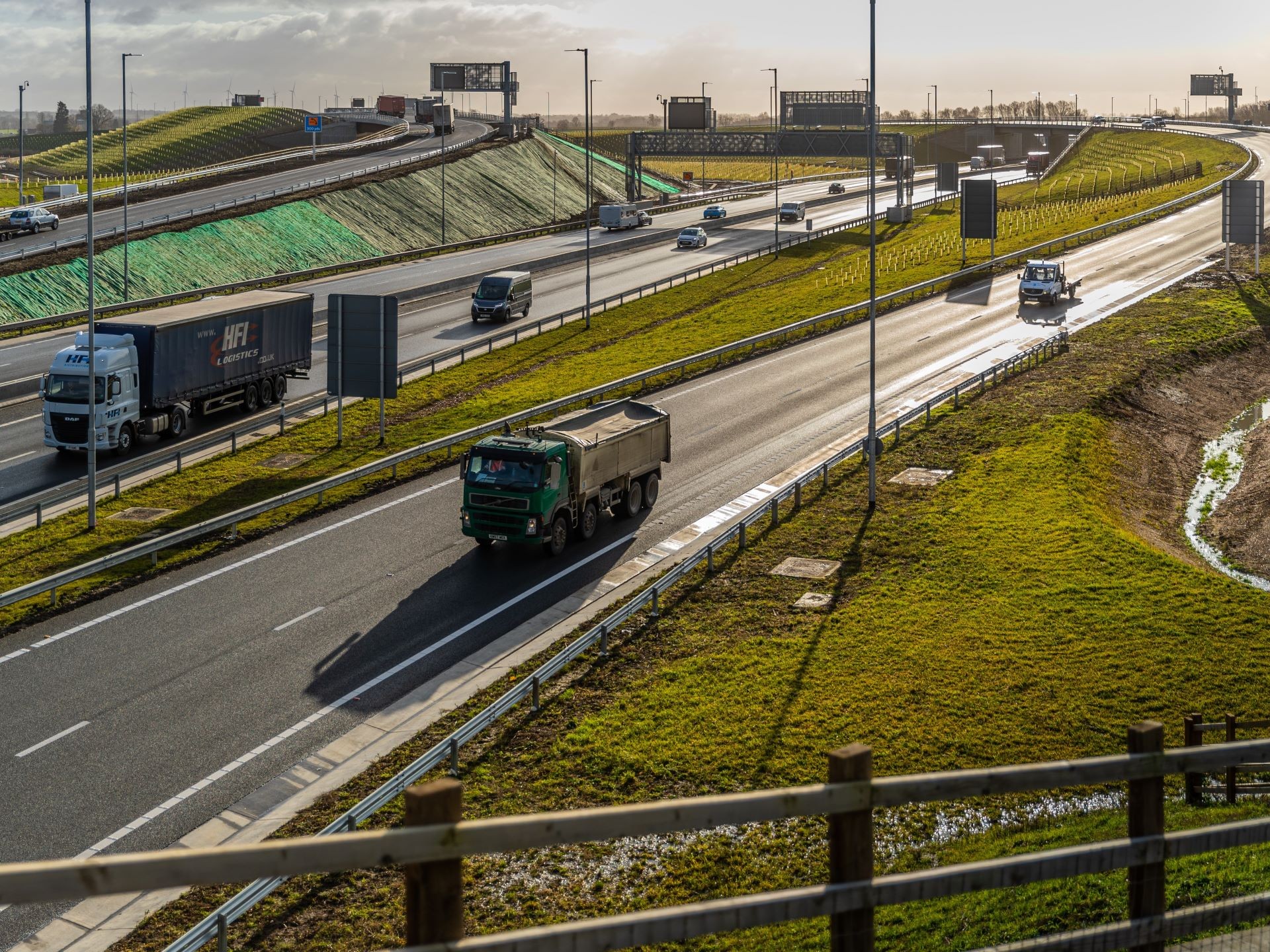 Busy highway with trucks and cars traveling on multiple lanes under daylight.