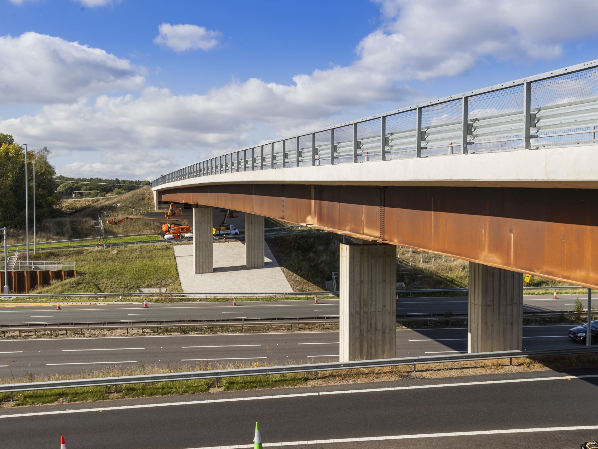 Modern highway overpass bridge with clear blue sky background Modern concrete and steel highway bridge over multiple lanes under a partly cloudy sky.