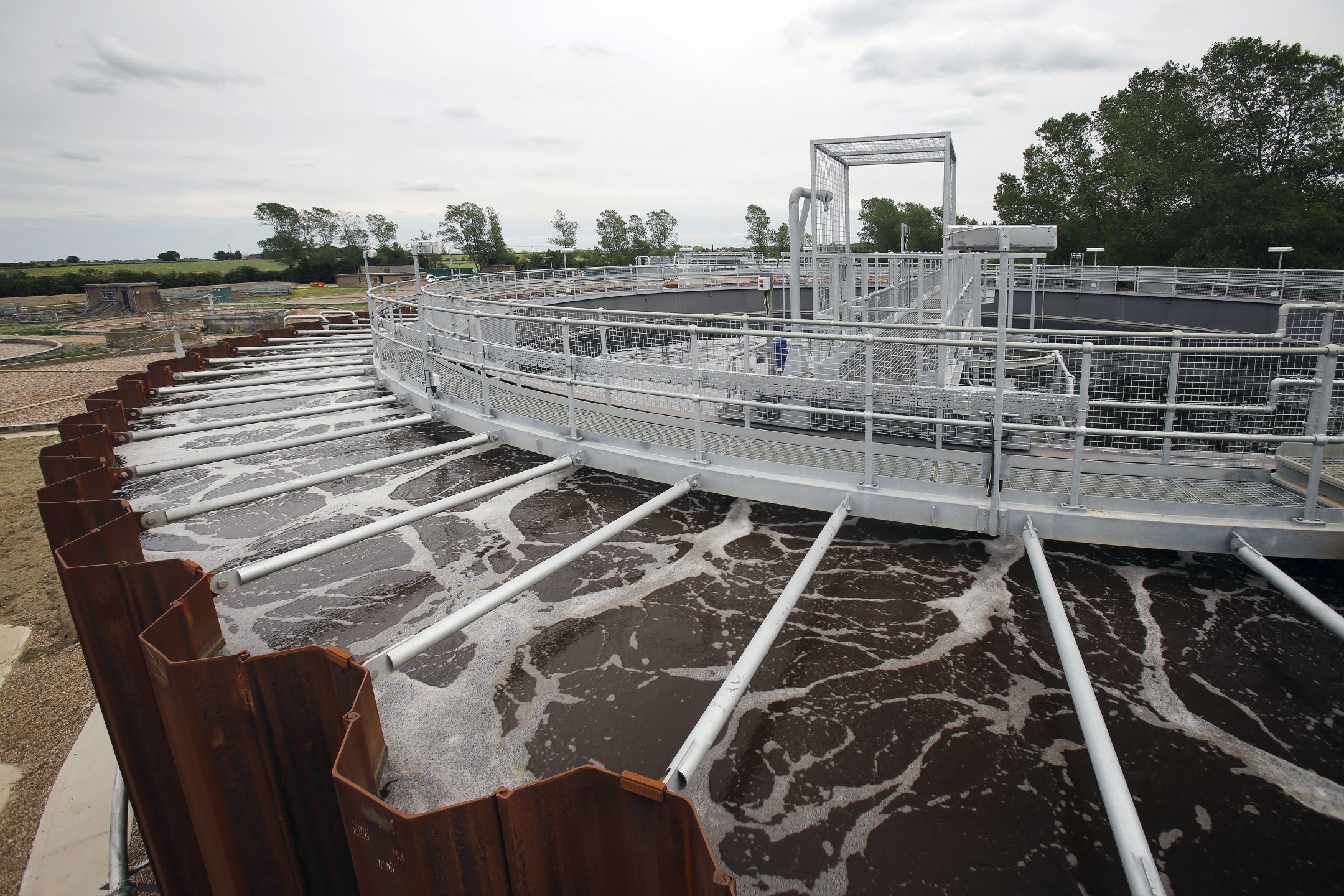 Modern Wastewater Treatment Plant with Aeration Tank System A large circular wastewater treatment tank with aeration pipes and metal railings.