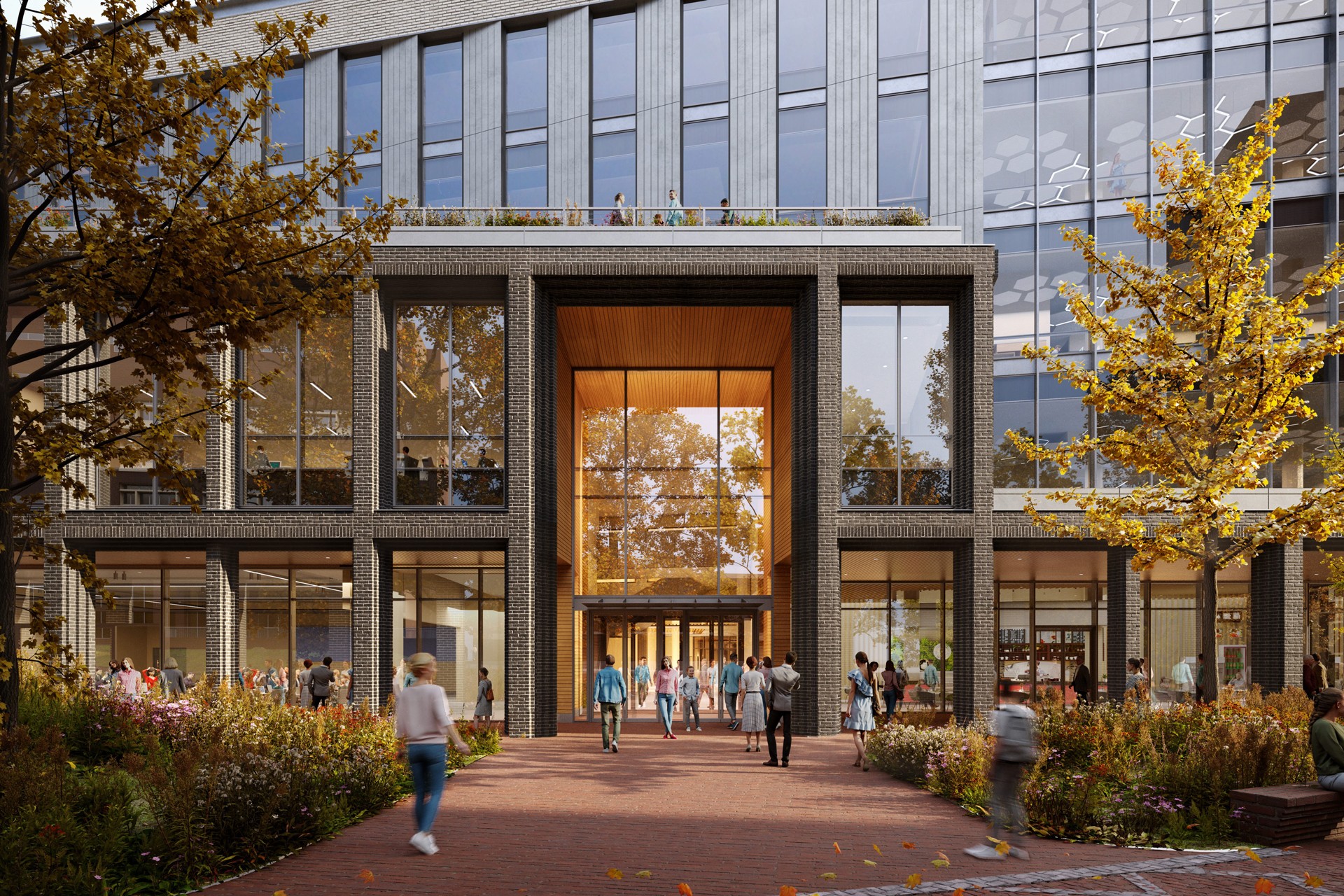 Modern office building entrance with glass windows, brick pathway, and people walking.