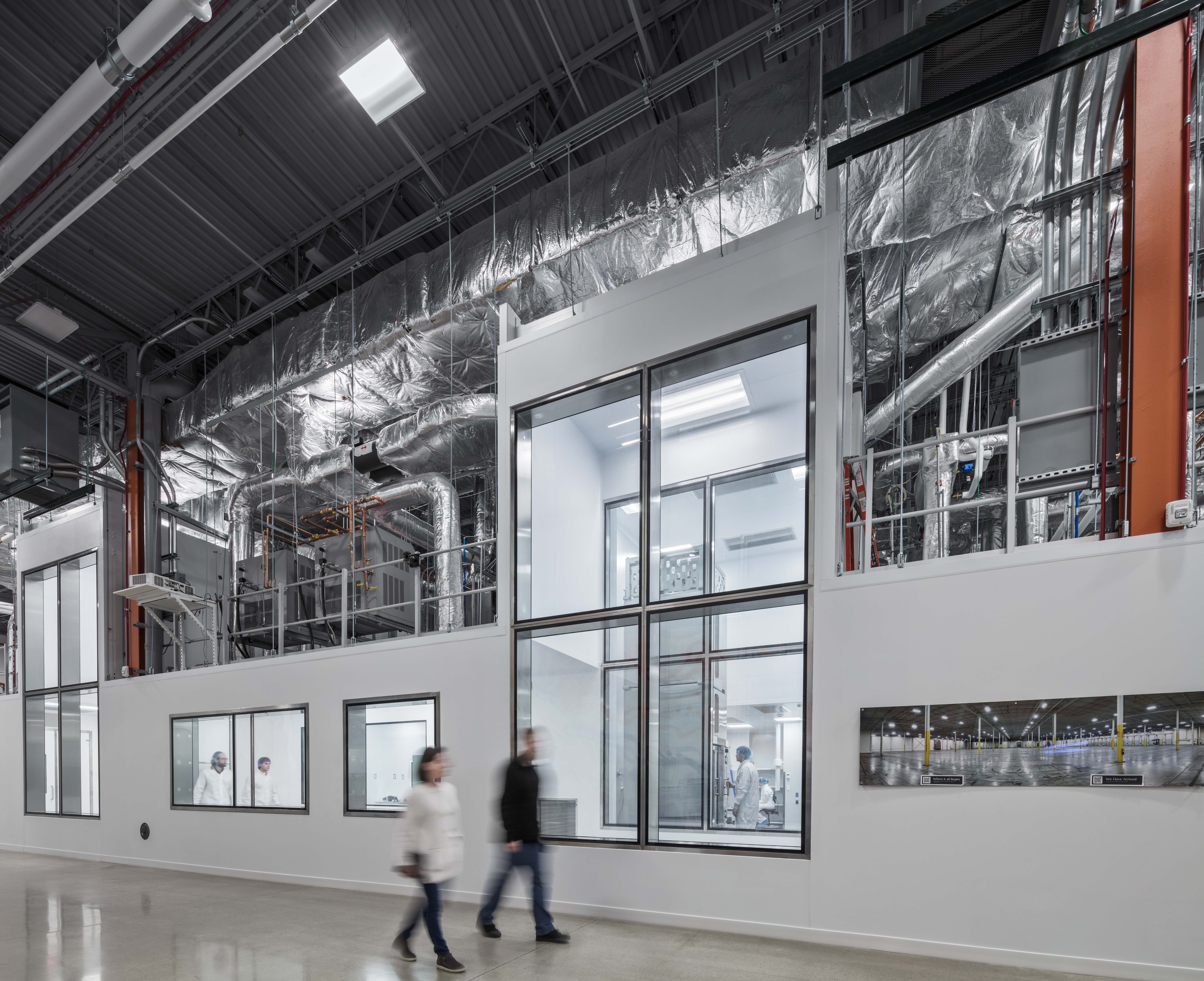 Two people walking in a clean room lab Two people walking in a clean room lab