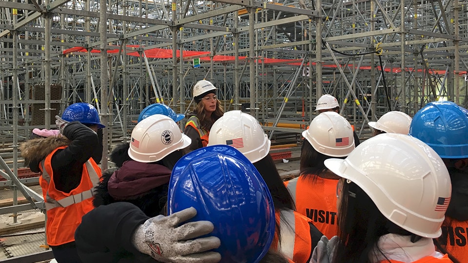 Group of construction workers wearing helmets and safety vests at a building site.
