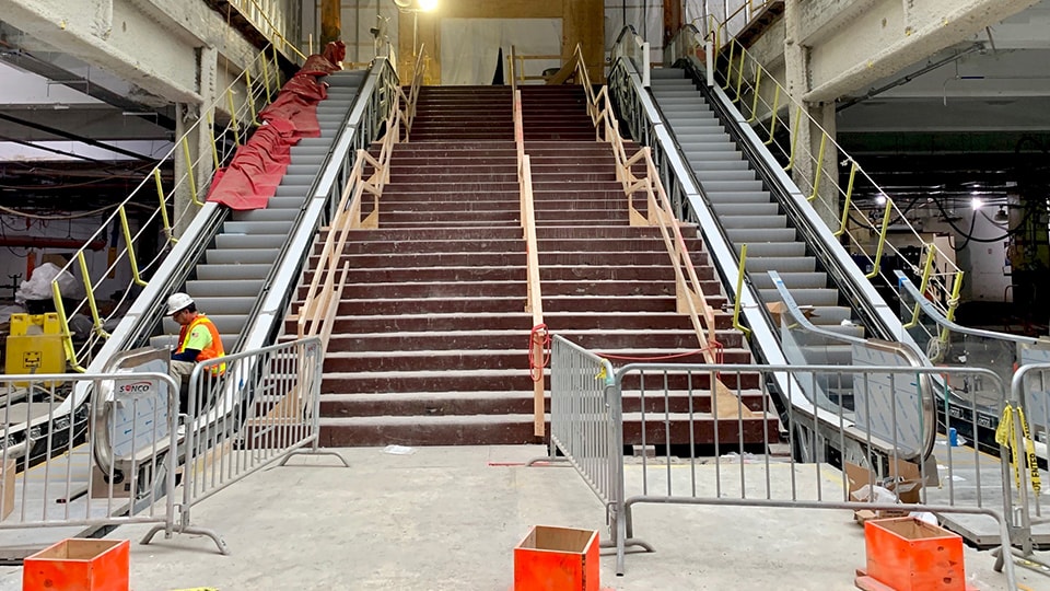 Construction site with escalators and stairs in a building under renovation.