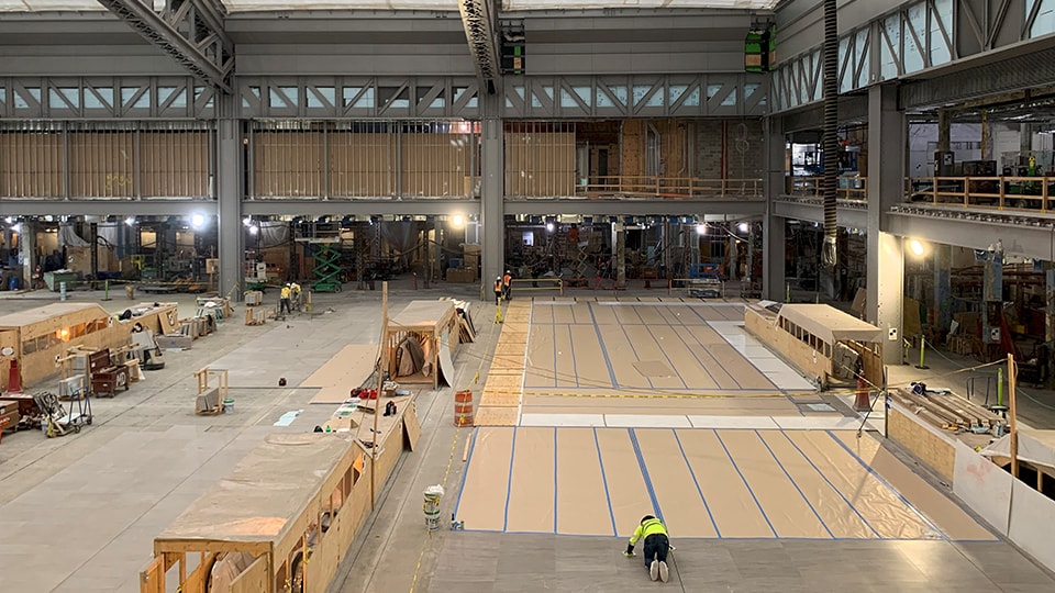 Large industrial warehouse under construction with workers and building materials inside.