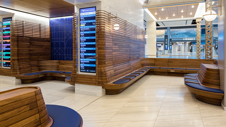 Modern train station waiting area with wooden benches and digital schedule boards.