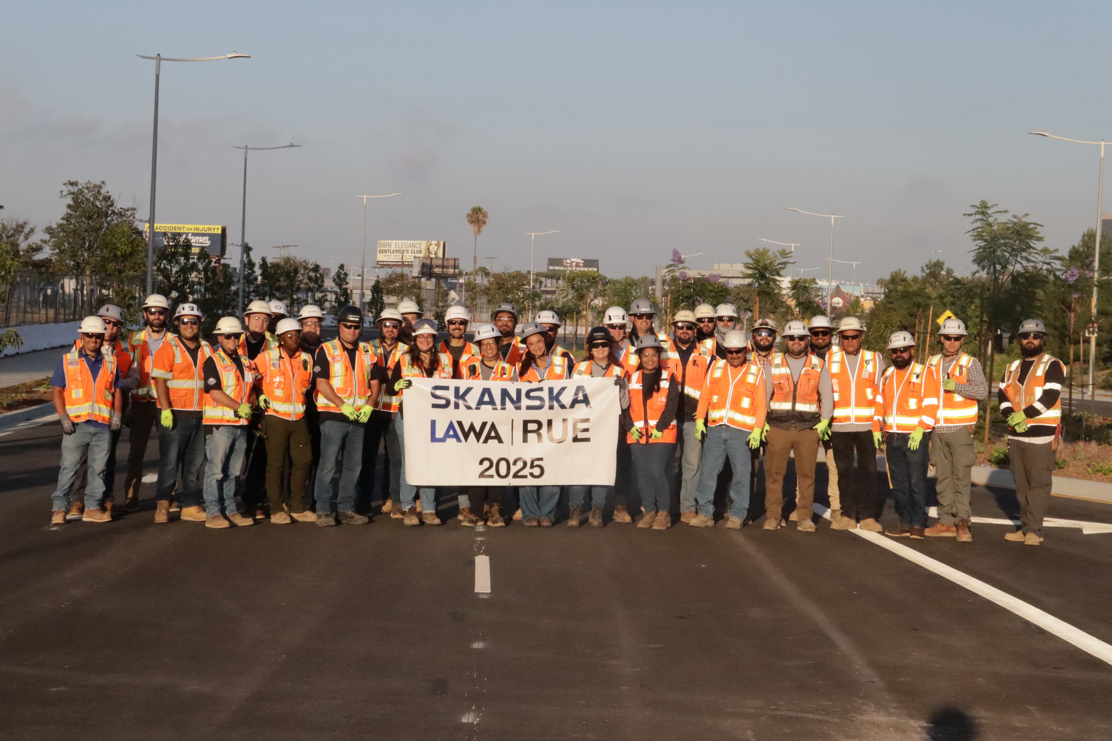 Group of construction workers in safety gear holding a Skanska LAWA RUE 2025 banner.