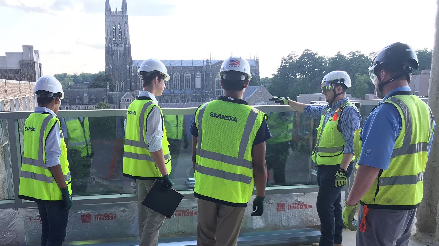 Construction workers in safety gear inspecting a site with a cathedral in the background.