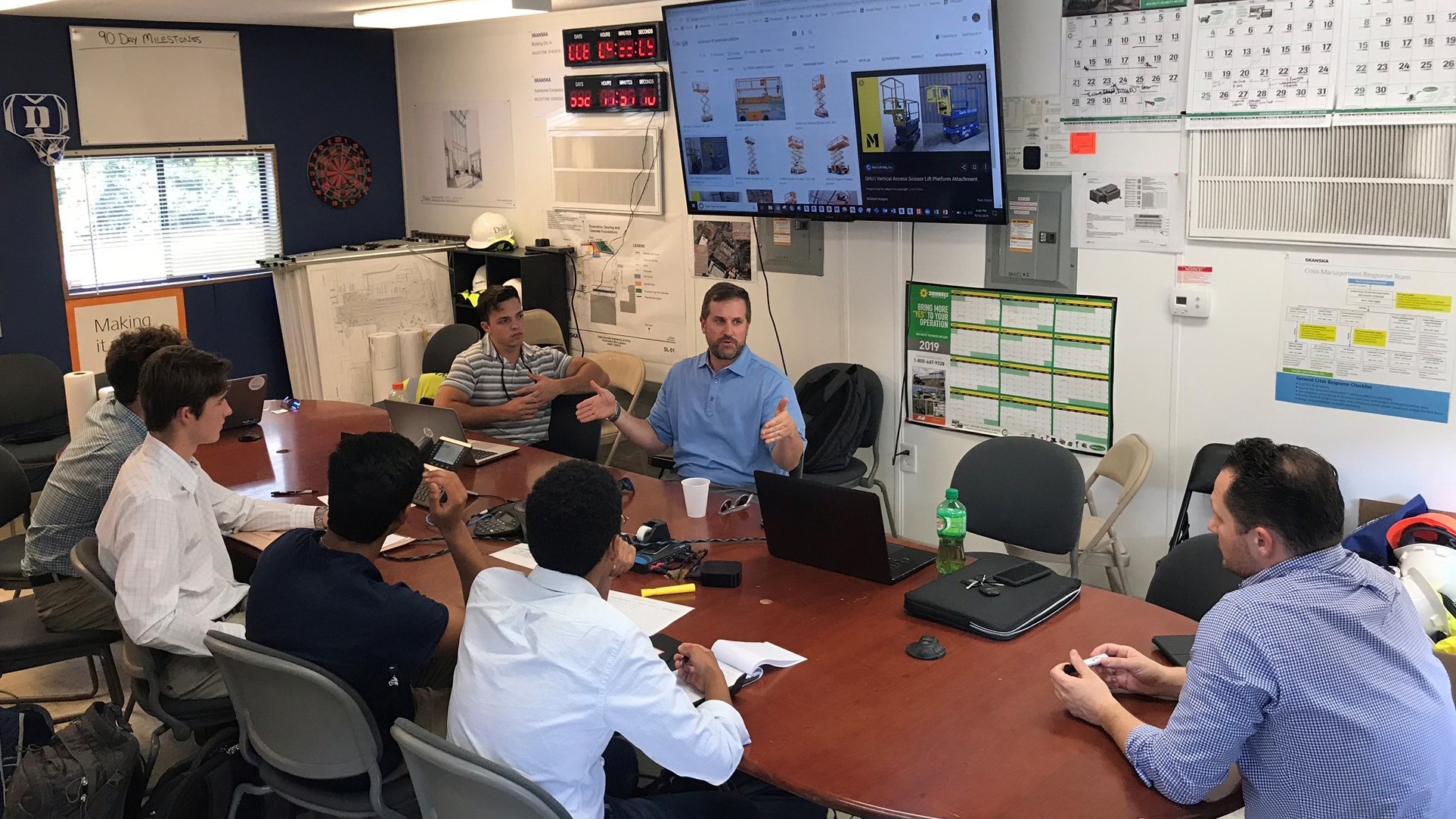 Team of professionals in a meeting room discussing data with laptops and charts visible.