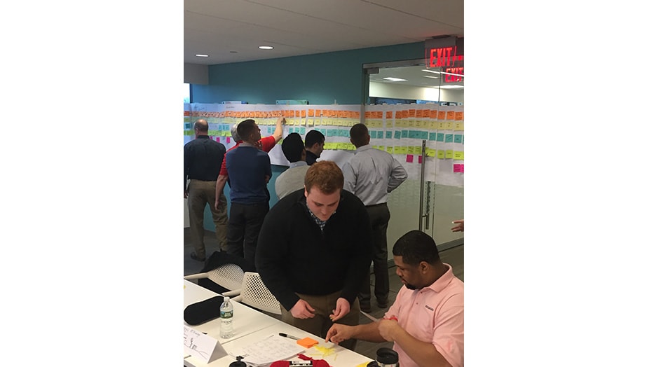 Team collaborating in an office using colorful sticky notes on a glass wall for planning.