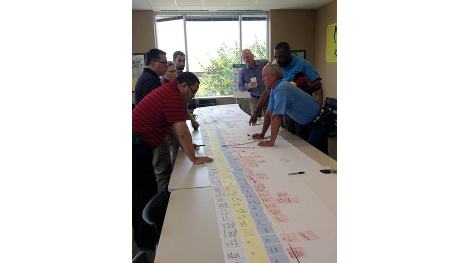 Team of professionals collaborating over a detailed project timeline on a long table.