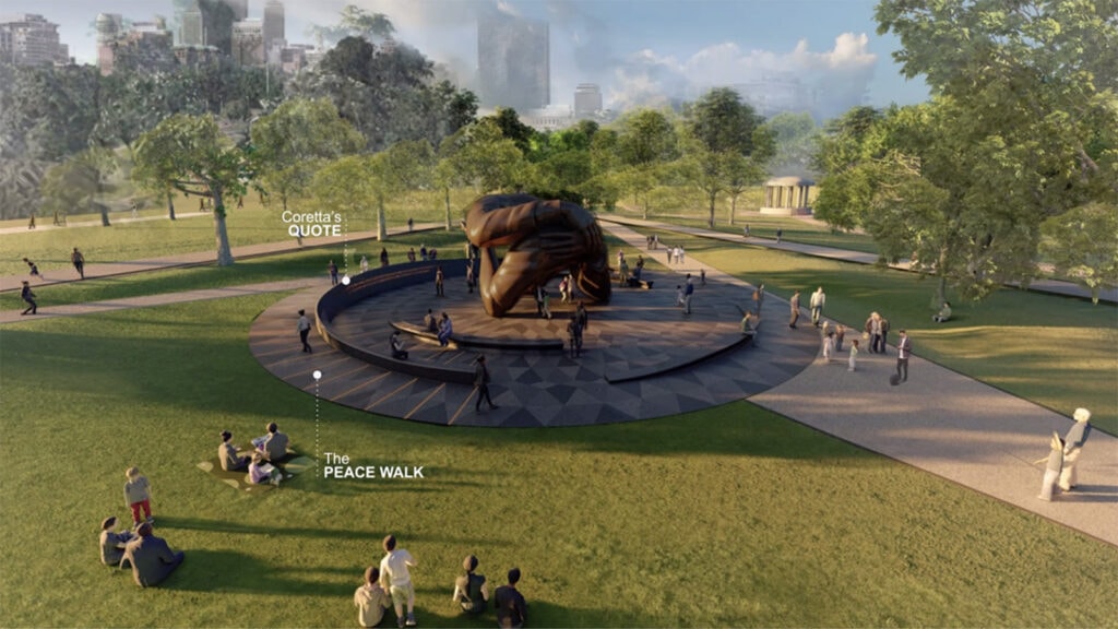 Large outdoor sculpture of a resting figure in a park with people walking and sitting nearby.