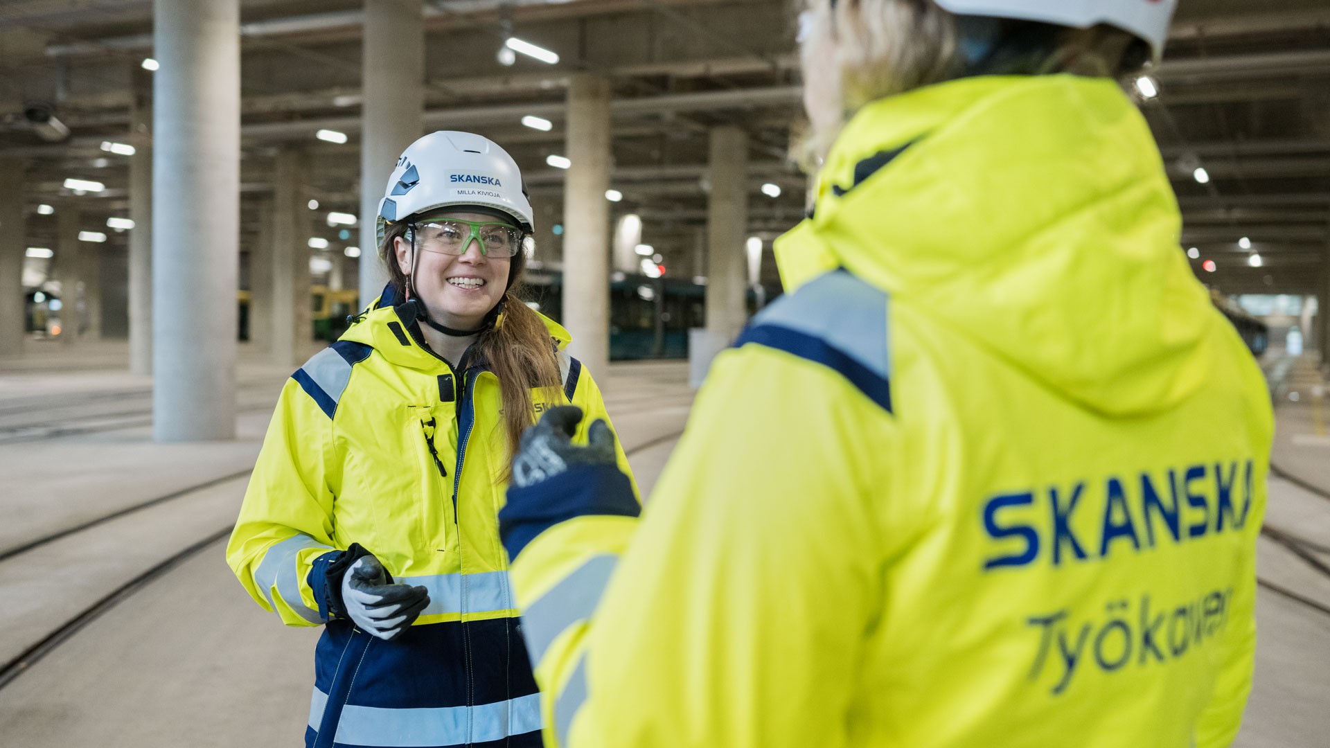 Milla Kivioja suojavarusteissaan työmaalla yhdessä työkaverinsa kanssa