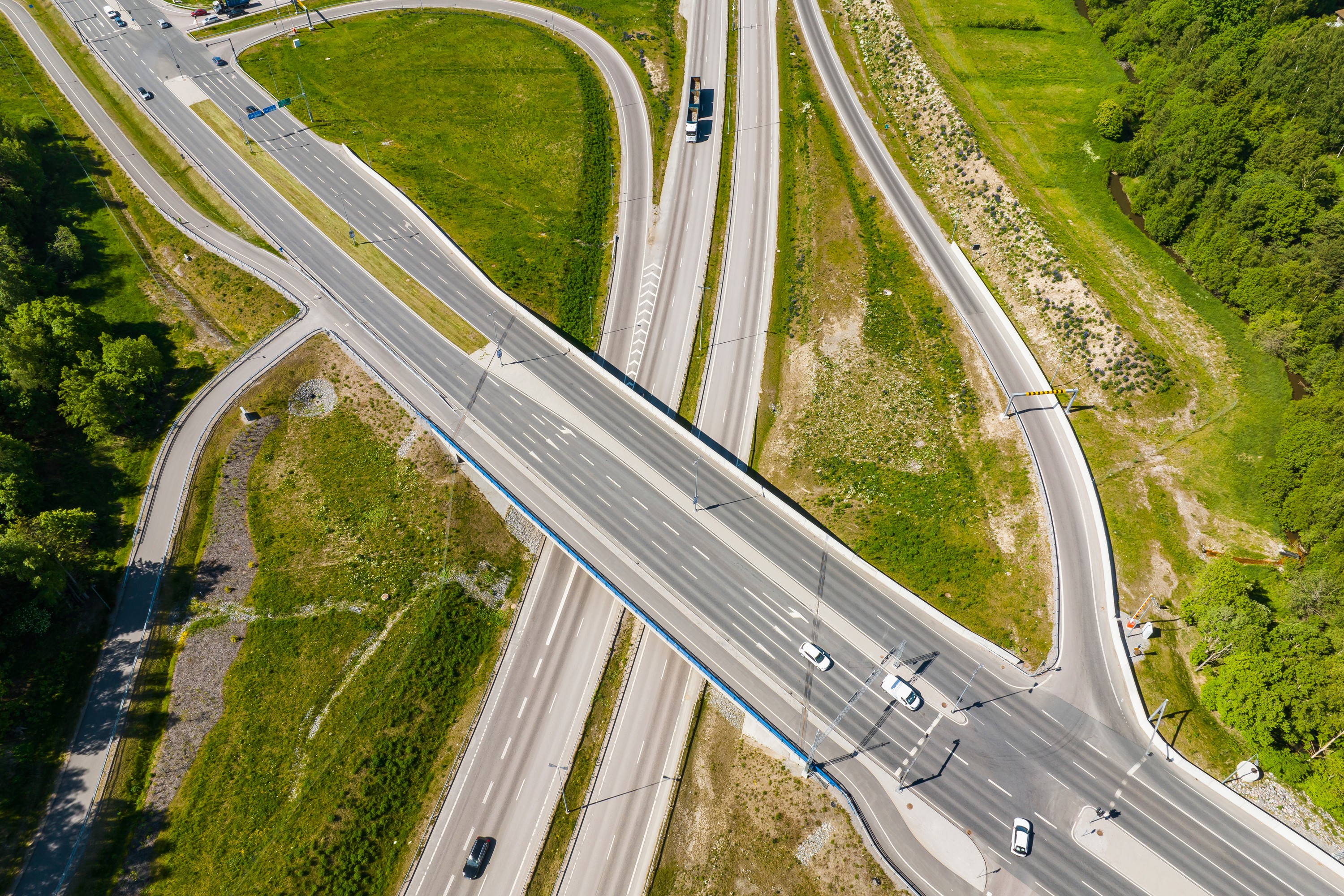 Aerial view of a highway interchange with cars, surrounded by green grass and trees.