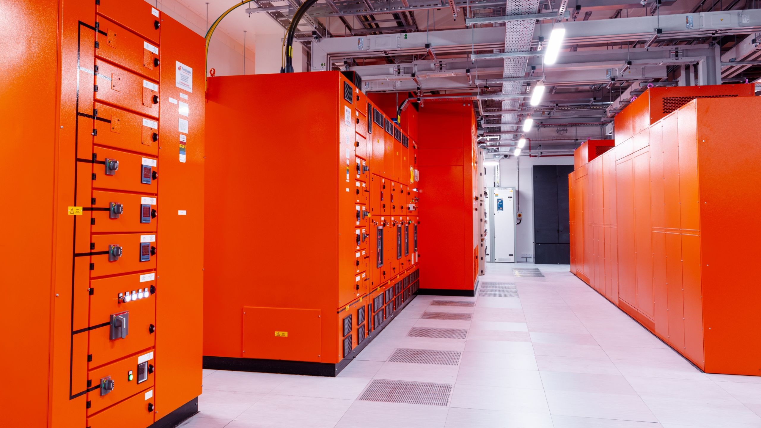 Modern Industrial Electrical Control Room with Orange Panels Interior view of a brightly lit data center with vibrant orange server cabinets.
