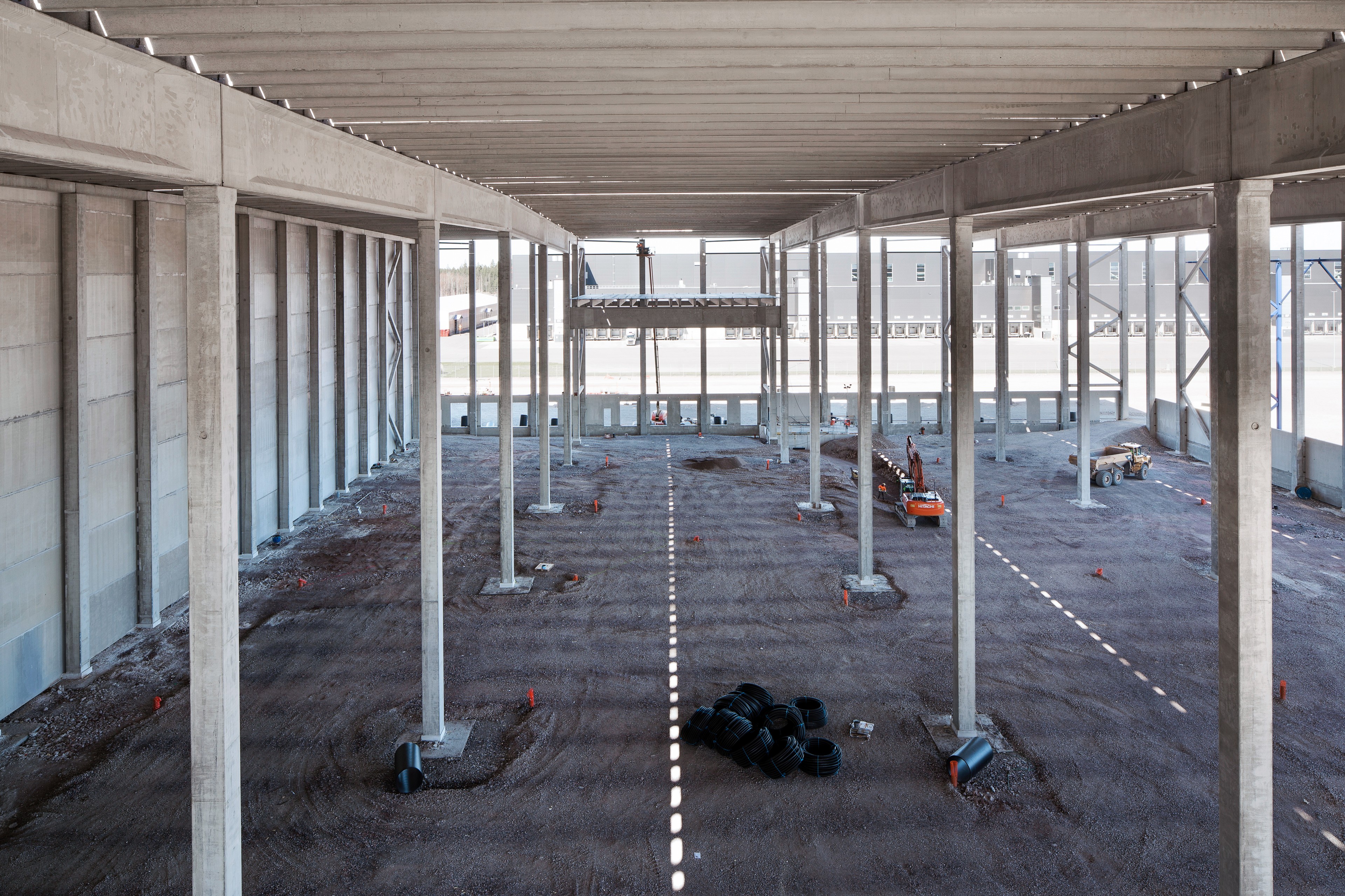 Interior construction site with concrete pillars and gravel floor.