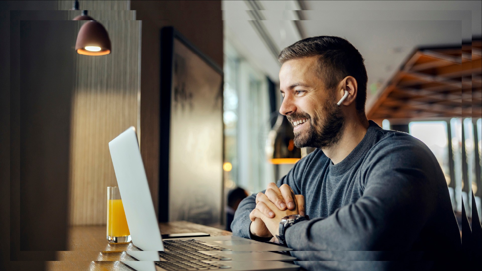 Mies työskentelee kahvilassa kannettavalla tietokoneella, kuulokkeet korvissa. Mies, jolla on korvakuulokkeet, työskentelee kannettavalla tietokoneella kahvilassa.
