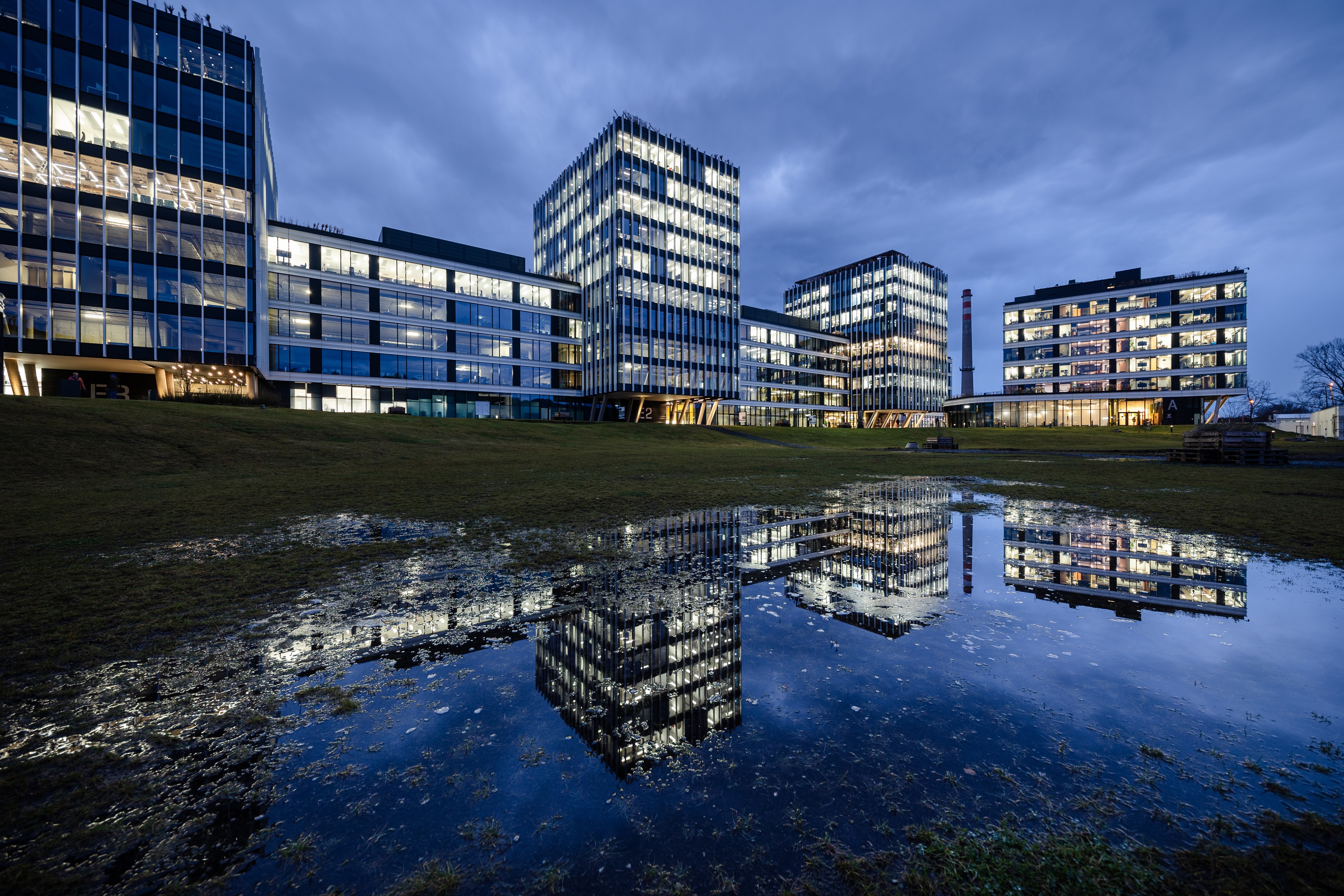 Port7 at night after the rain Modern office buildings reflected in a large puddle of water during twilight with a cloudy sky.